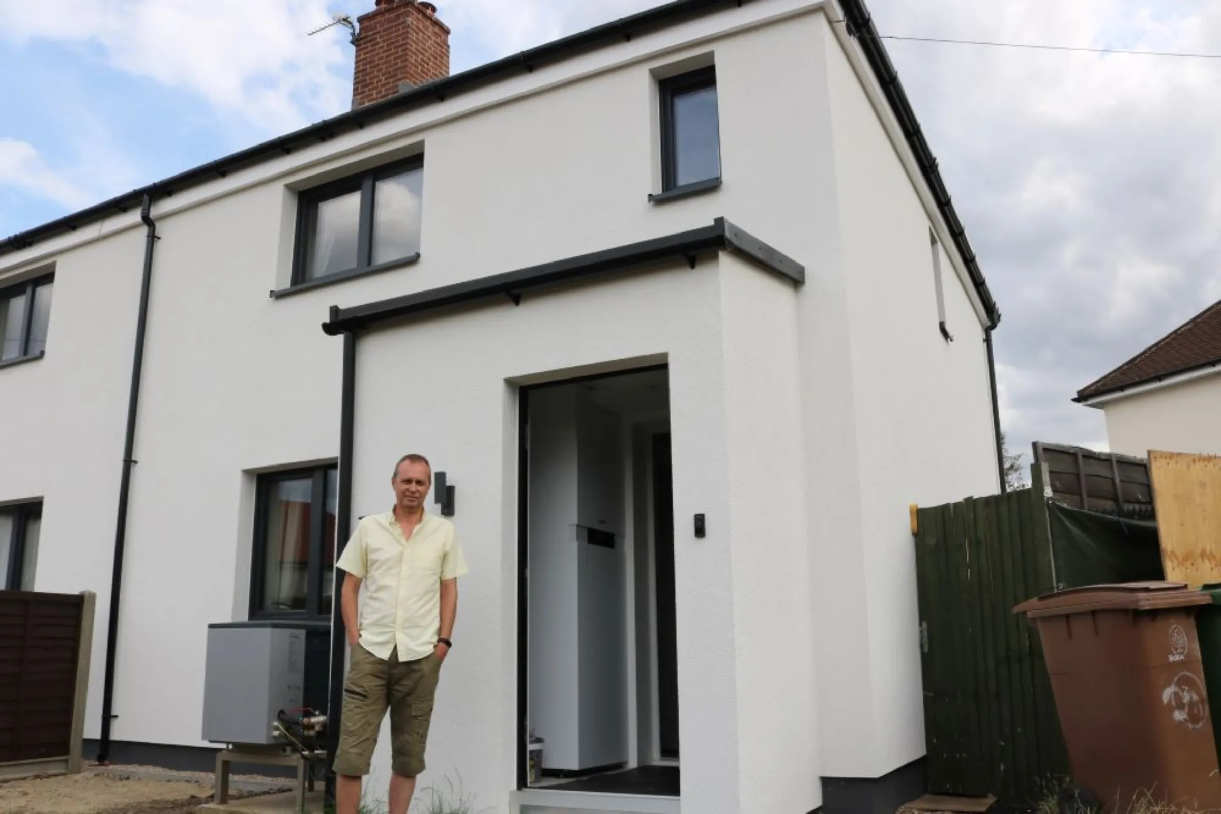 A man stands outside a white residential home