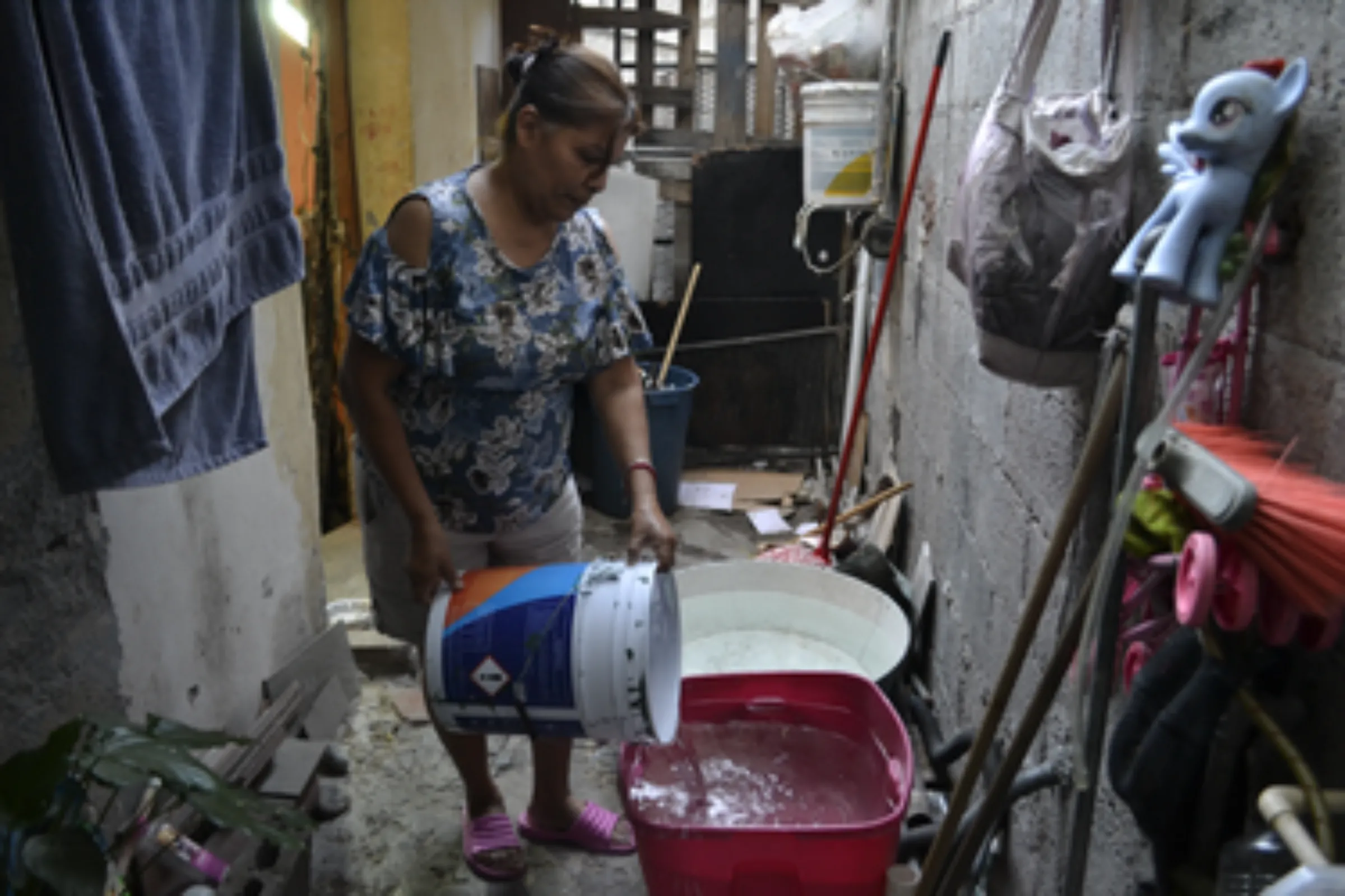 A woman, Maria Juárez, fills a container with water at her house in Monterrey, Nuevo Leon, Mexico. May 15, 2022. Thomson Reuters Foundation/Diana Baptista