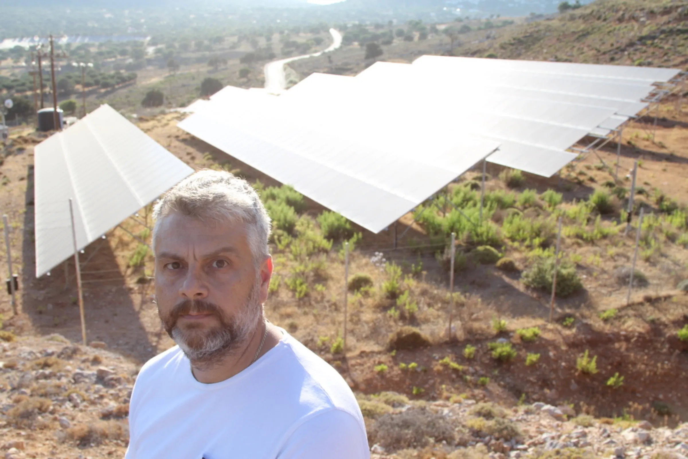 Tilos municipality secretary-general Eustathios Kontos stands before a solar panel installation