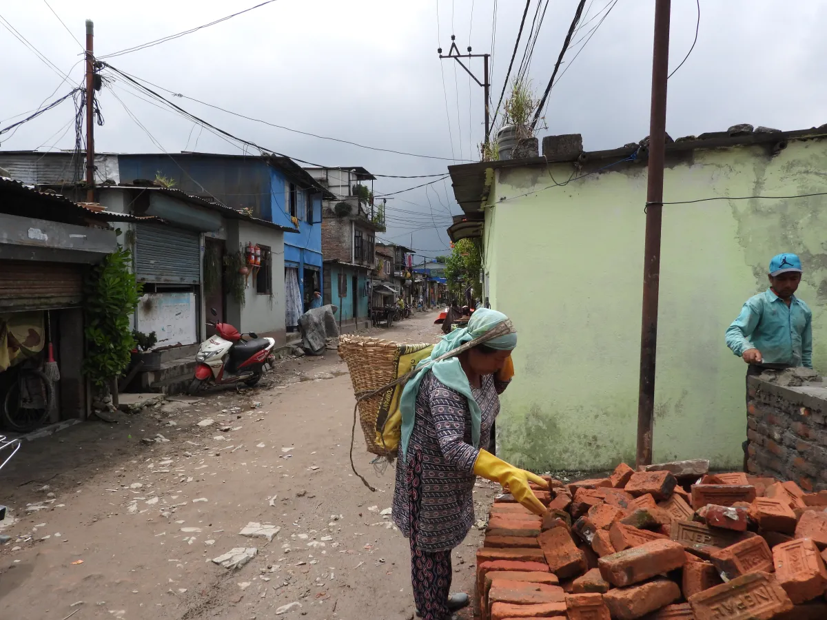 A woman examines a pile of bricks in a slum on the outskirts of Kathmandu, Nepal, September 8, 2022