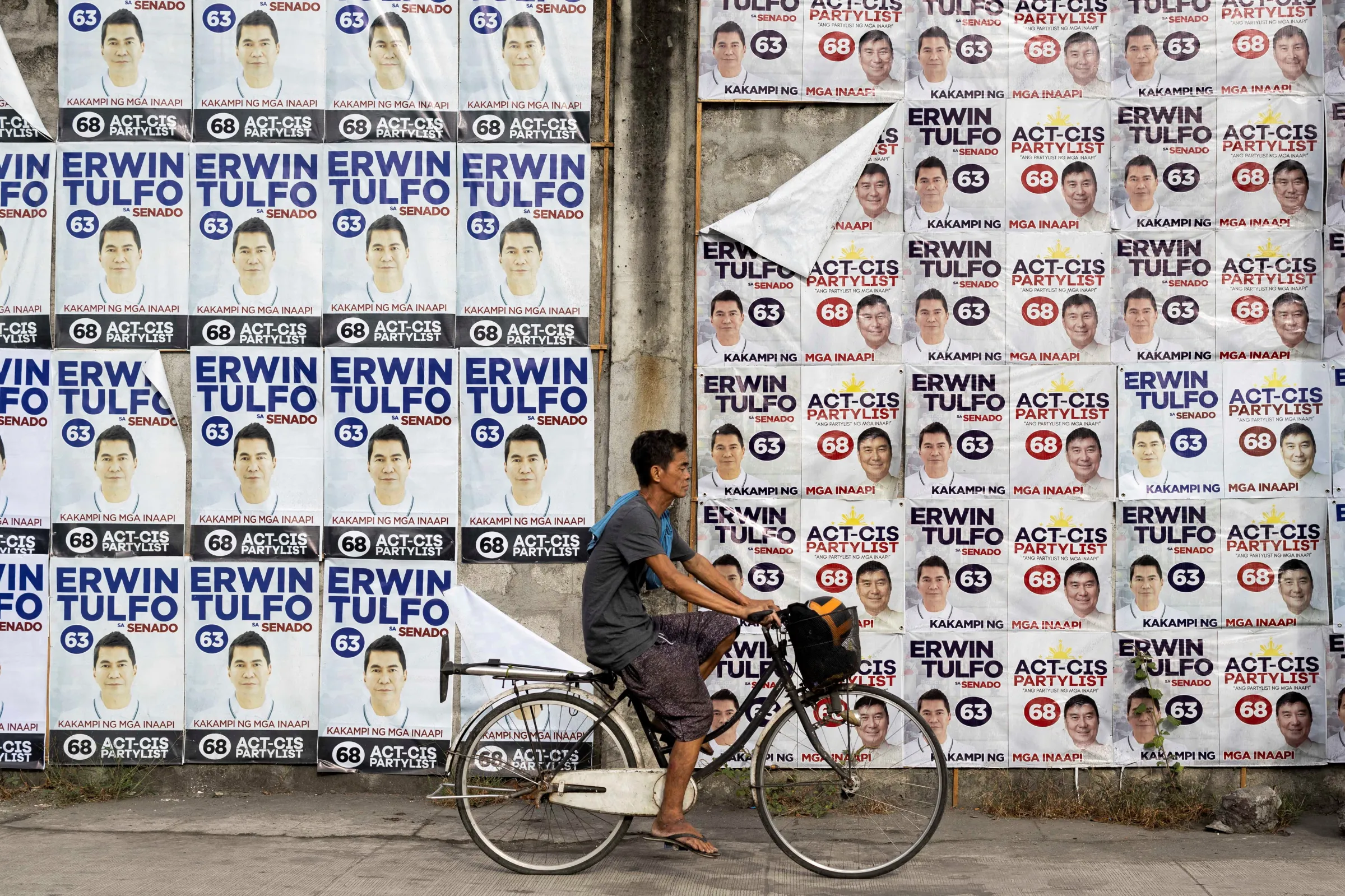 A man bikes past a wall of campaign posters for senatorial candidate Erwin Tulfo on the first day of the campaign period for the May 12 midterm elections, in Manila, Philippines, February 11, 2025. REUTERS/Eloisa Lopez