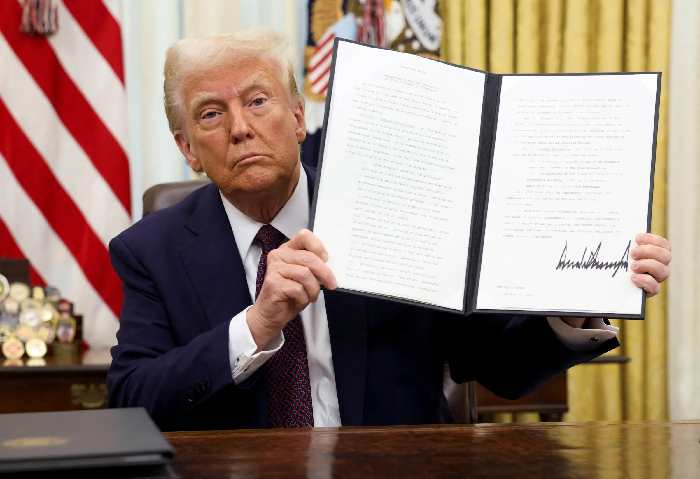 U.S. President Donald Trump holds a signed executive order on cryptocurrencies, in the Oval Office of the White House, in Washington, U.S., January 23, 2025. REUTERS/Kevin Lamarque