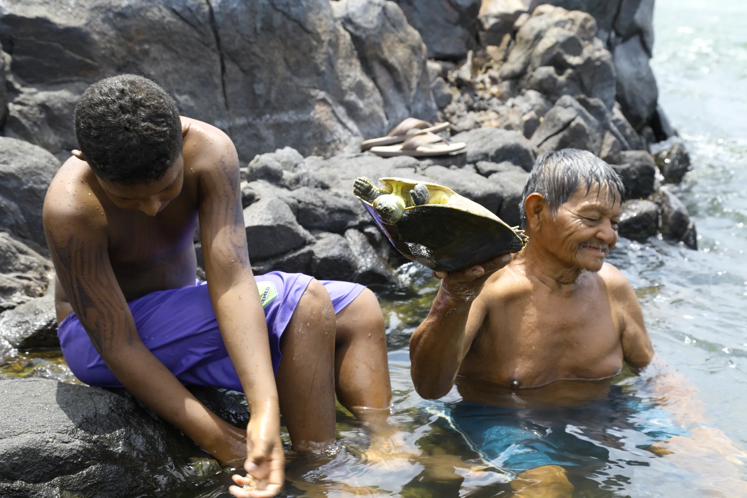 Old and young indigenous people hold tracajá turtles at Jericoa, a sacred site with a confluence of waterfalls and rapids on the Volta Grande in the River Xingu, Pará, Brazil, September 16, 2022. Thomson Reuters Foundation/Dan Collyns