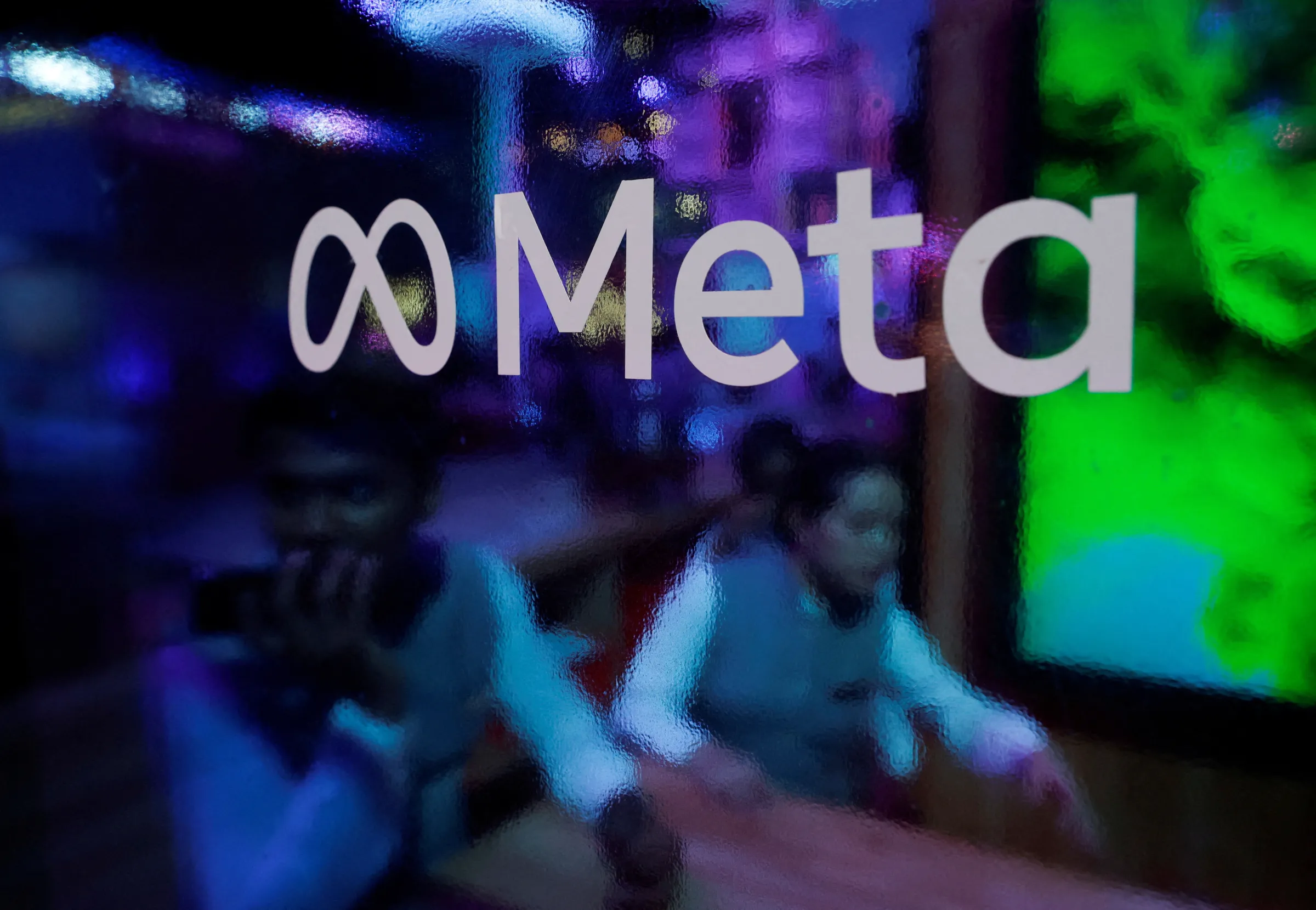 People are seen behind a logo of Meta Platforms, during a conference in Mumbai, India, September 20, 2023. REUTERS/Francis Mascarenhas