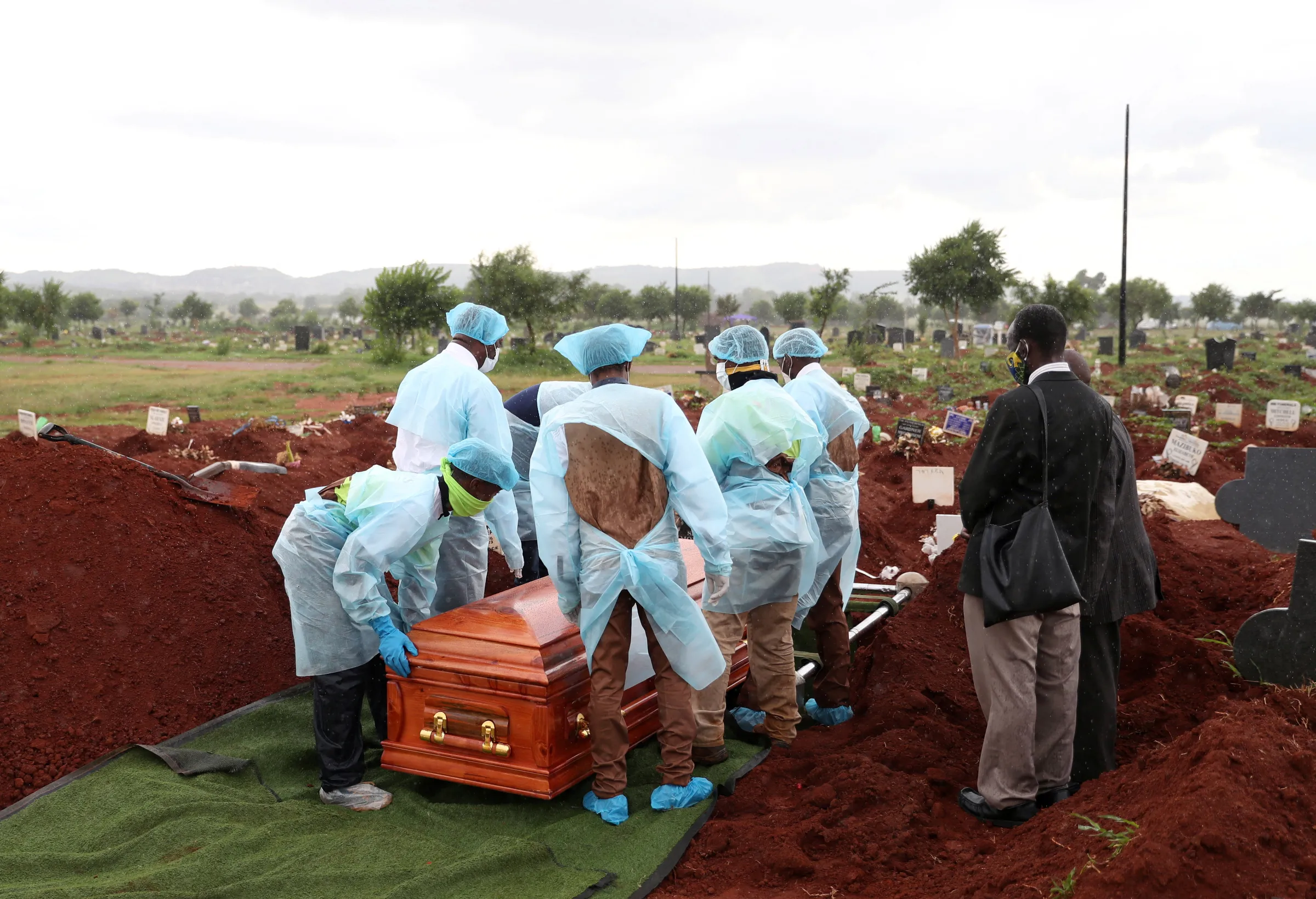 Funeral workers wearing personal protective equipment carry a casket during the burial of a COVID-19 victim, amid a nationwide coronavirus disease (COVID-19) lockdown, at the Olifantsvlei cemetery, south-west of Joburg, South Africa January 6, 2021. REUTERS/Siphiwe Sibeko
