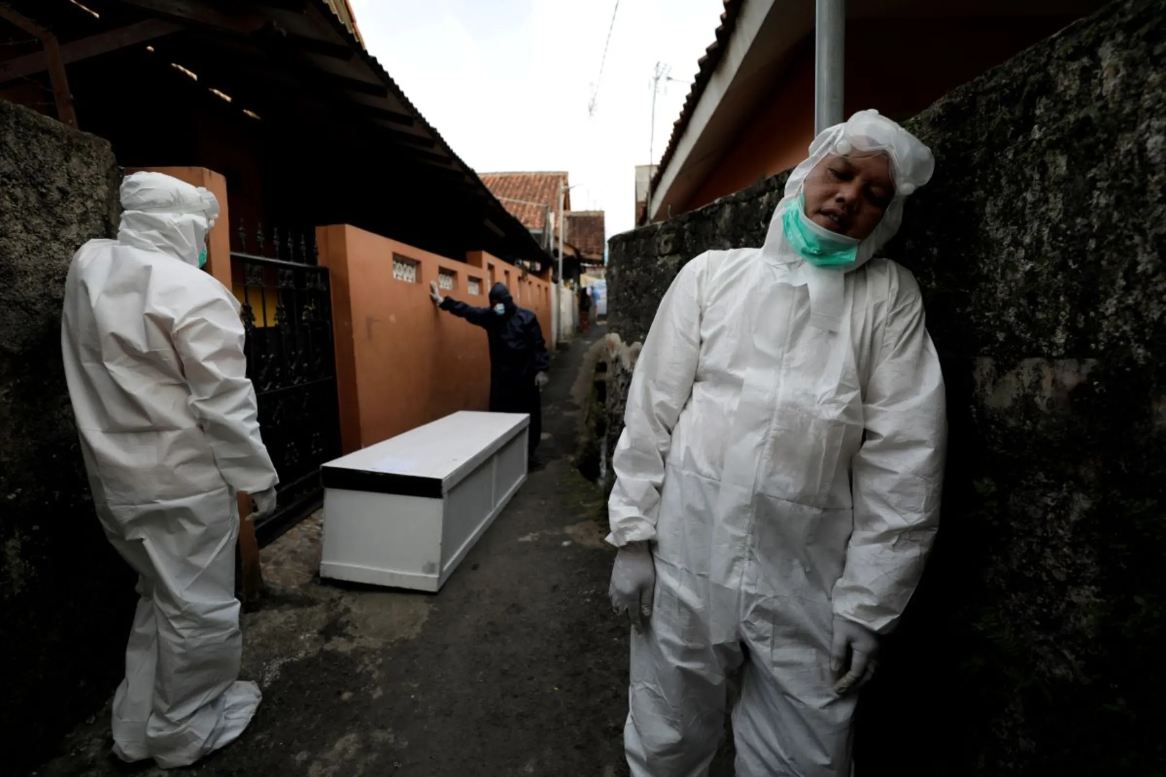 A volunteer undertaker wears personal protective equipment as he takes a short-break while carrying the coffin of a 64-year-old who passed away due to complications related to COVID-19 whilst isolating at her home in Bogor, West Java province, Indonesia, July 8, 2021. REUTERS/Willy Kurniawan