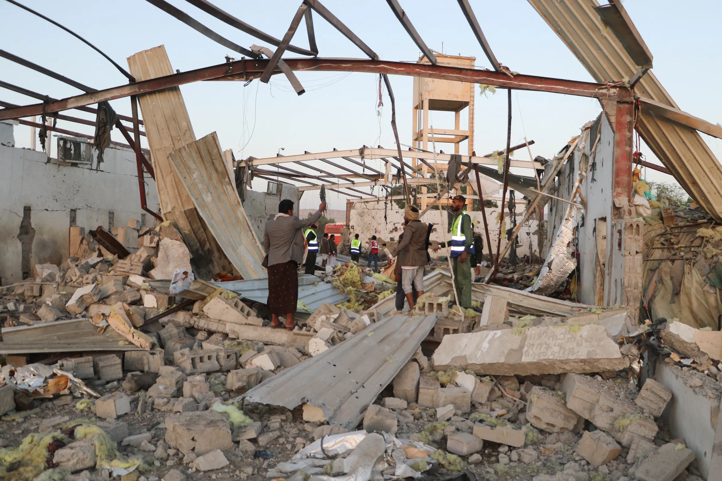 Rescuers stand at the site of a strike at a detention centre hosting African migrants, in Saada, Yemen April 28, 2025. REUTERS/Naif Rahma