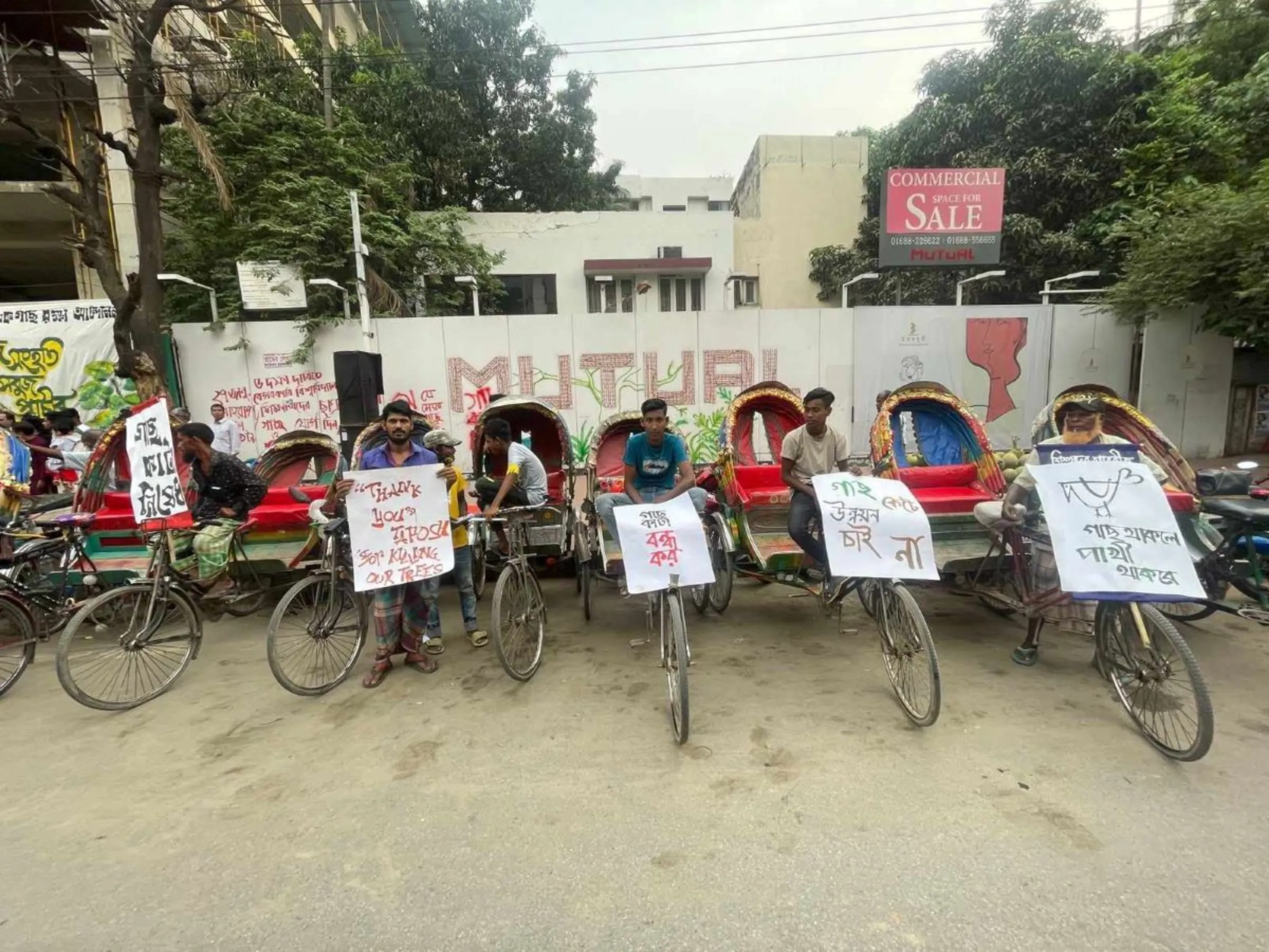 A row of rickshaw pullers hold up placards demanding protection of trees in Dhaka after hundreds of trees were cut down for roadwork, May 12, 2023