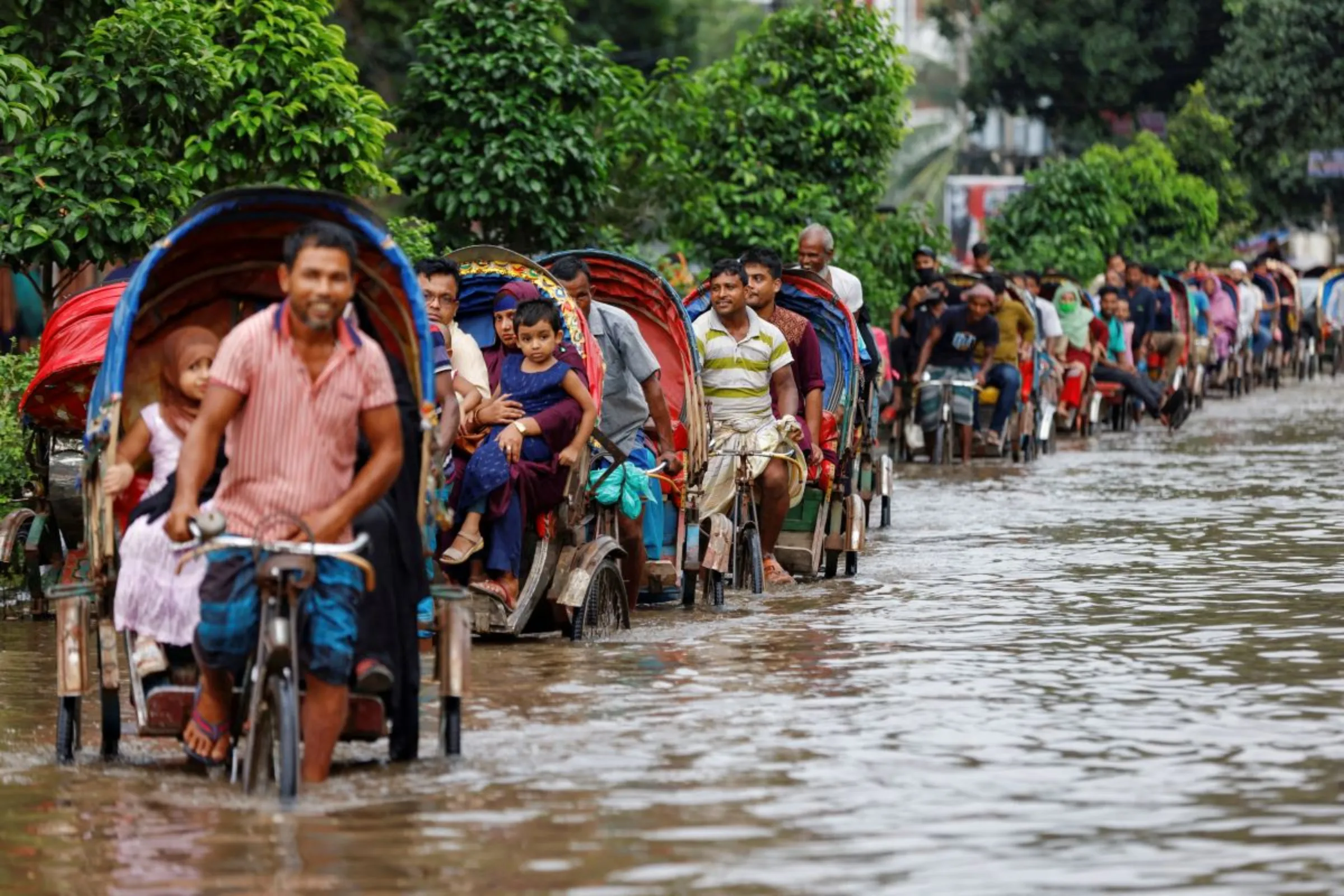 Commuters ride on rickshaws on a flooded road after heavy rains in Dhaka, Bangladesh, September 22, 2023