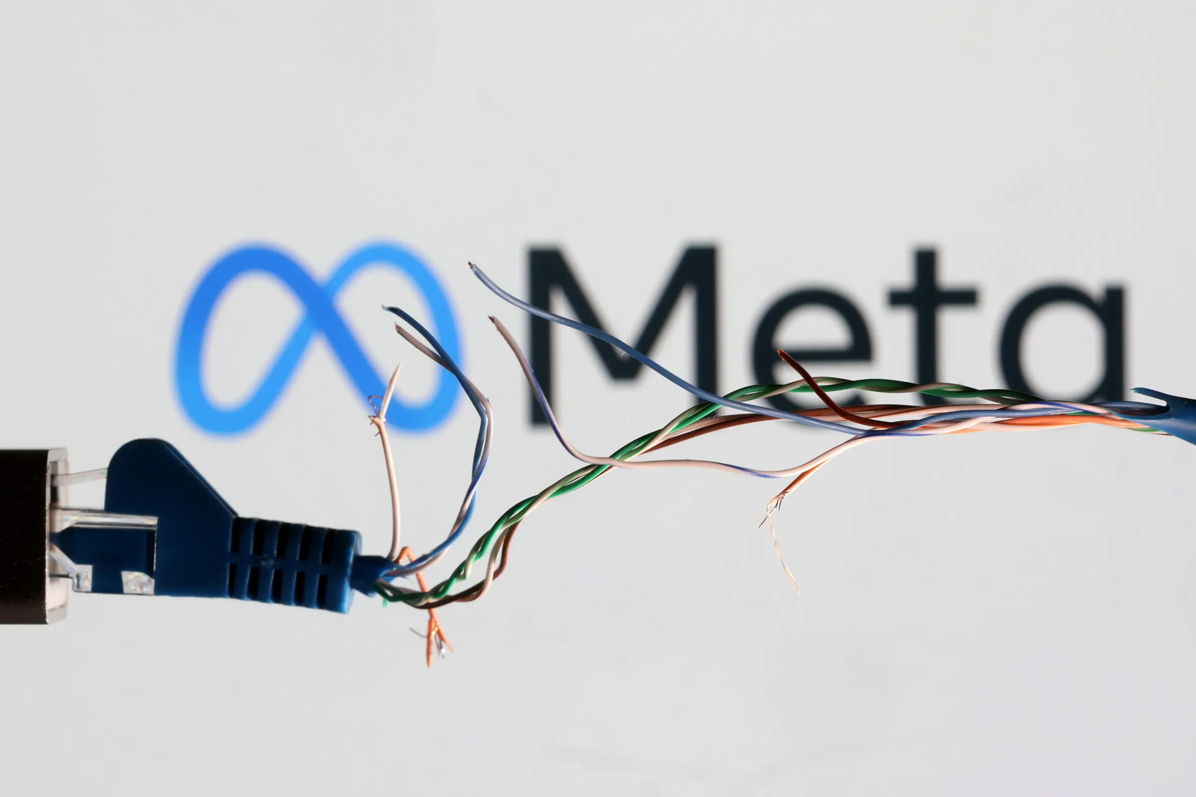 Broken Ethernet cable is seen in front of Meta logo in this illustration taken March 11, 2022