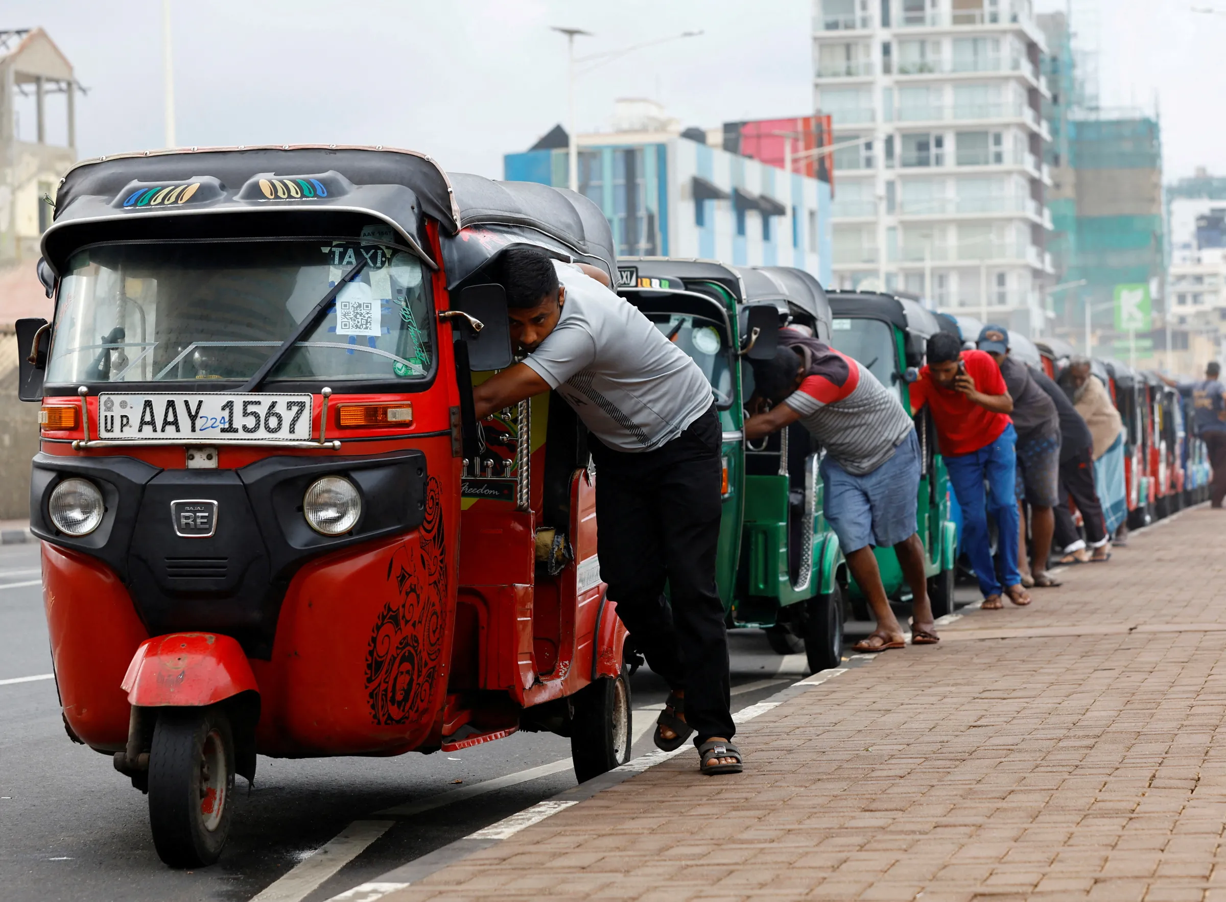 Drivers push auto rickshaws in a line to buy petrol from a fuel station, amid Sri Lanka's economic crisis, in Colombo, Sri Lanka, July 29, 2022