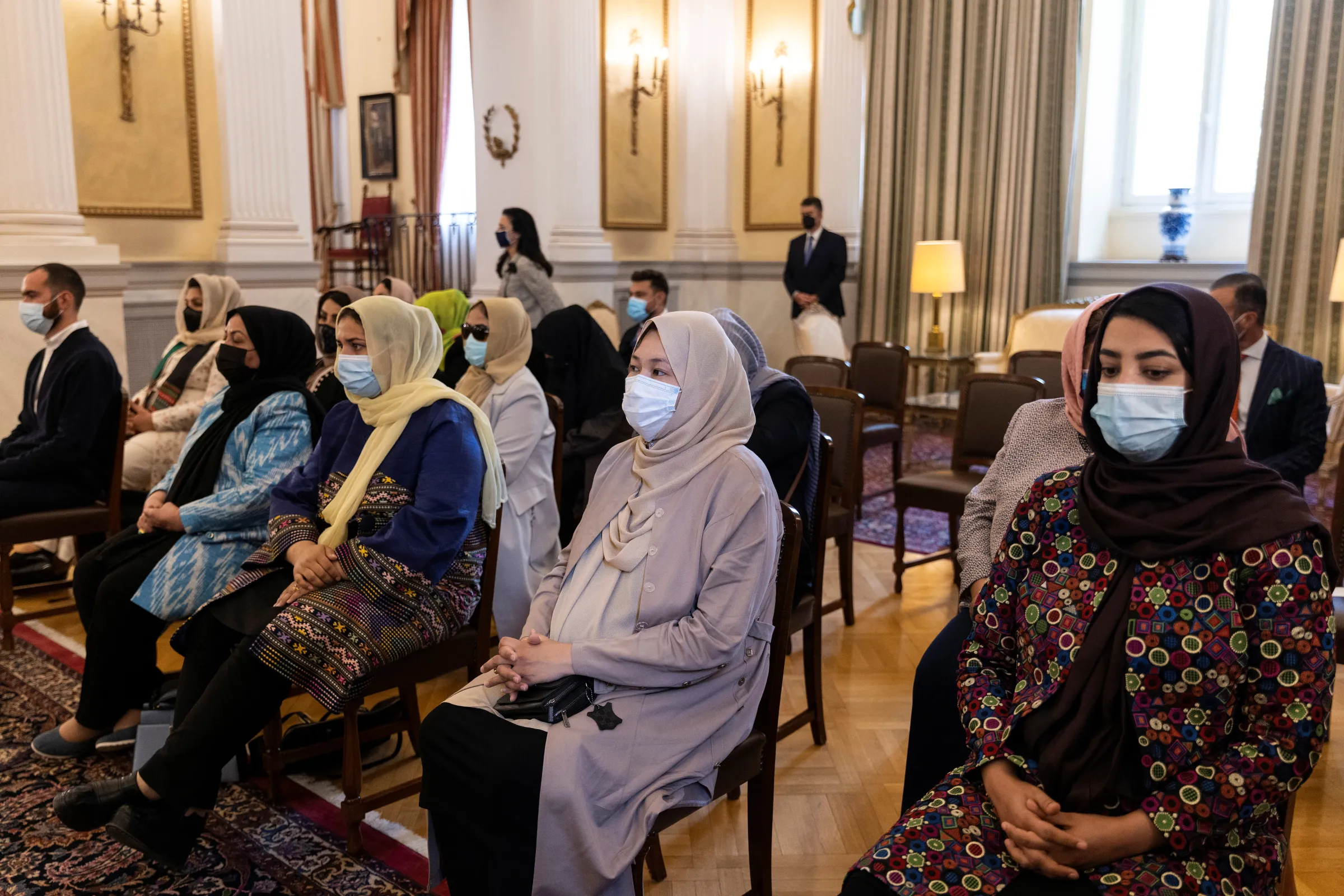Afghan women lawyers and judges, who fled Afghanistan following the Taliban takeover, sit in a room wearing facemasks
