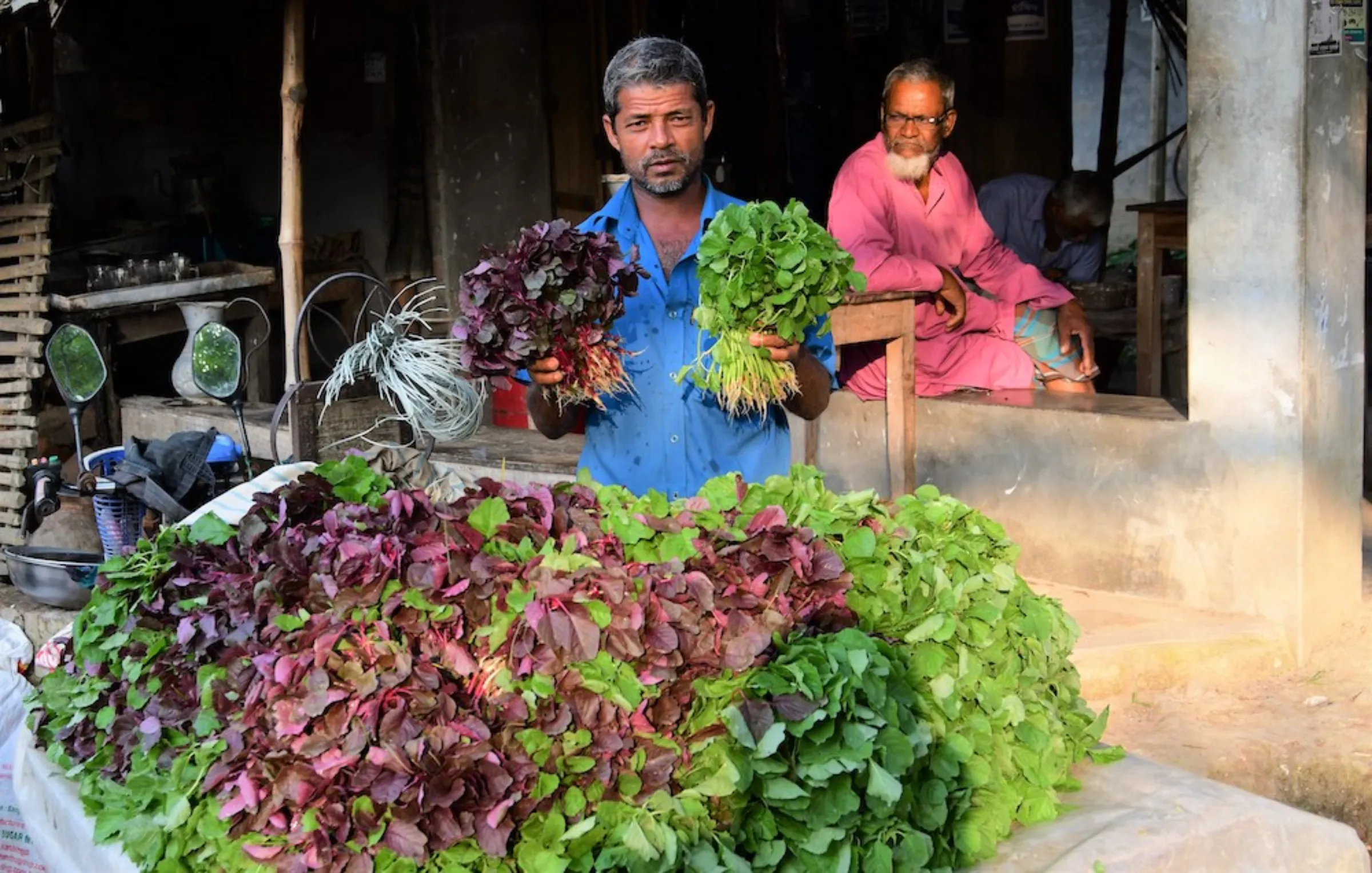 Farmer Jalal Mia sells the amaranth he grows on his farm in the parched Rajshahi region at a vegetable market in Natore district, Bangladesh, on October 28, 2022