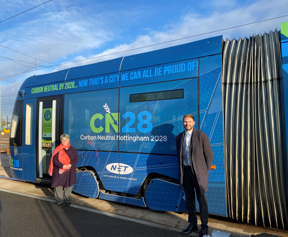 Councillor Sally Longford and Wayne Bexton, Director of Carbon Reduction at Nottingham City Council, pose beside a Nottingham Express Transit (NET) tram covered in Carbon Neutral Nottingham 2028 promotional livery in Nottingham, United Kingdom in an undated photograph.