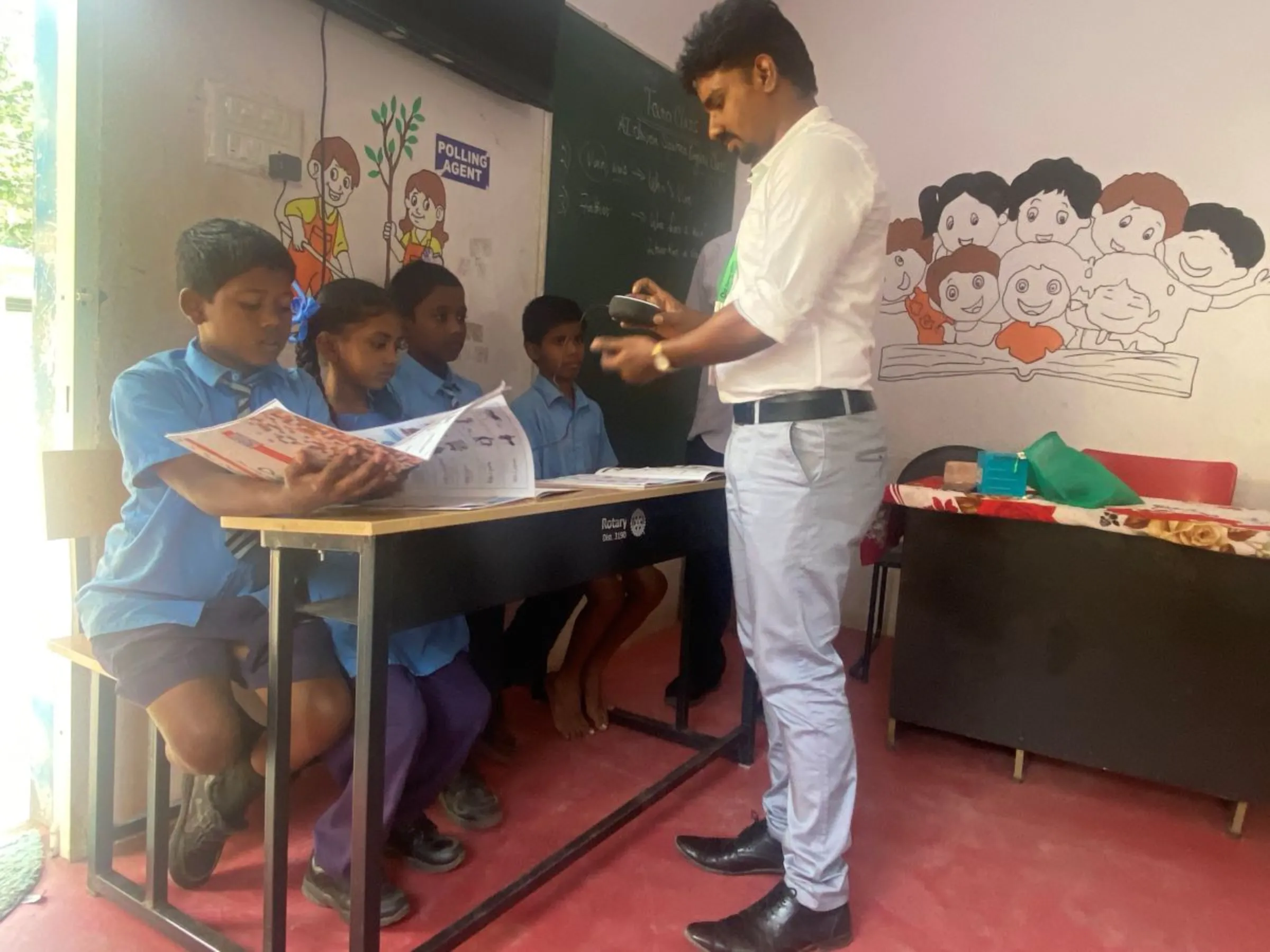 A teacher sets up an AI-enabled device for an English-language lesson in a government-funded school in the southern city of Bengaluru, India. October 5, 2023. Thomson Reuters Foundation/Rina Chandran