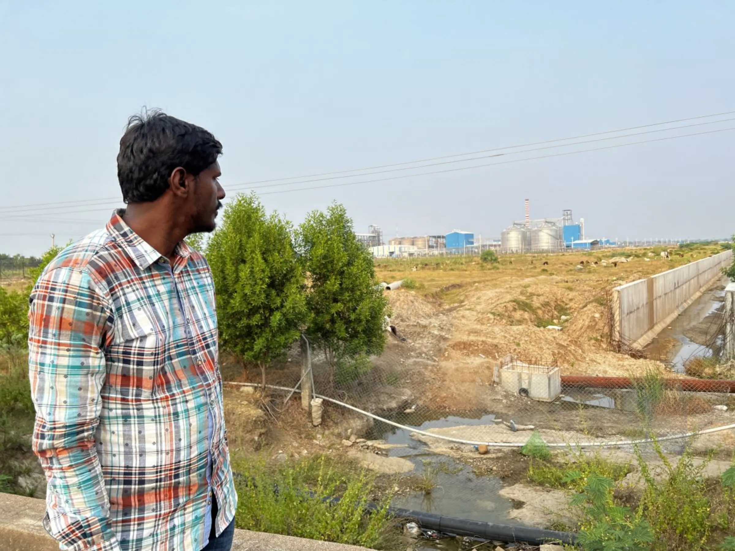 Sugunakar Reddy, a resident of Chittanur village, looks at a new ethanol plant which he says is polluting the stream that sustains his village in Telangana state, India, October 17, 2023