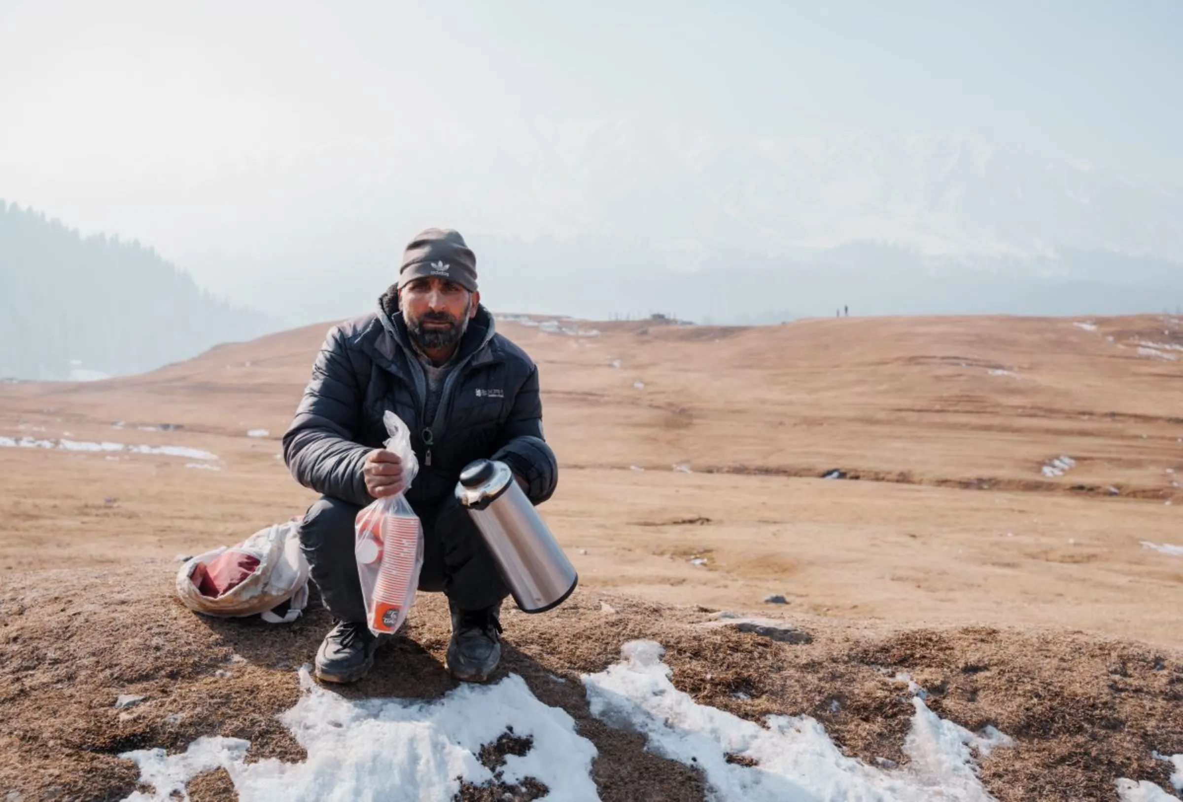 Abdul Rashid, a 45-year-old tea seller, awaits customers near Gulmarg, a Kashmiri winter sports town. The northern Indian region has seen little snowfall this year, Jan. 6, 2024. Thomson Reuters Foundation/Mehran Firdous
