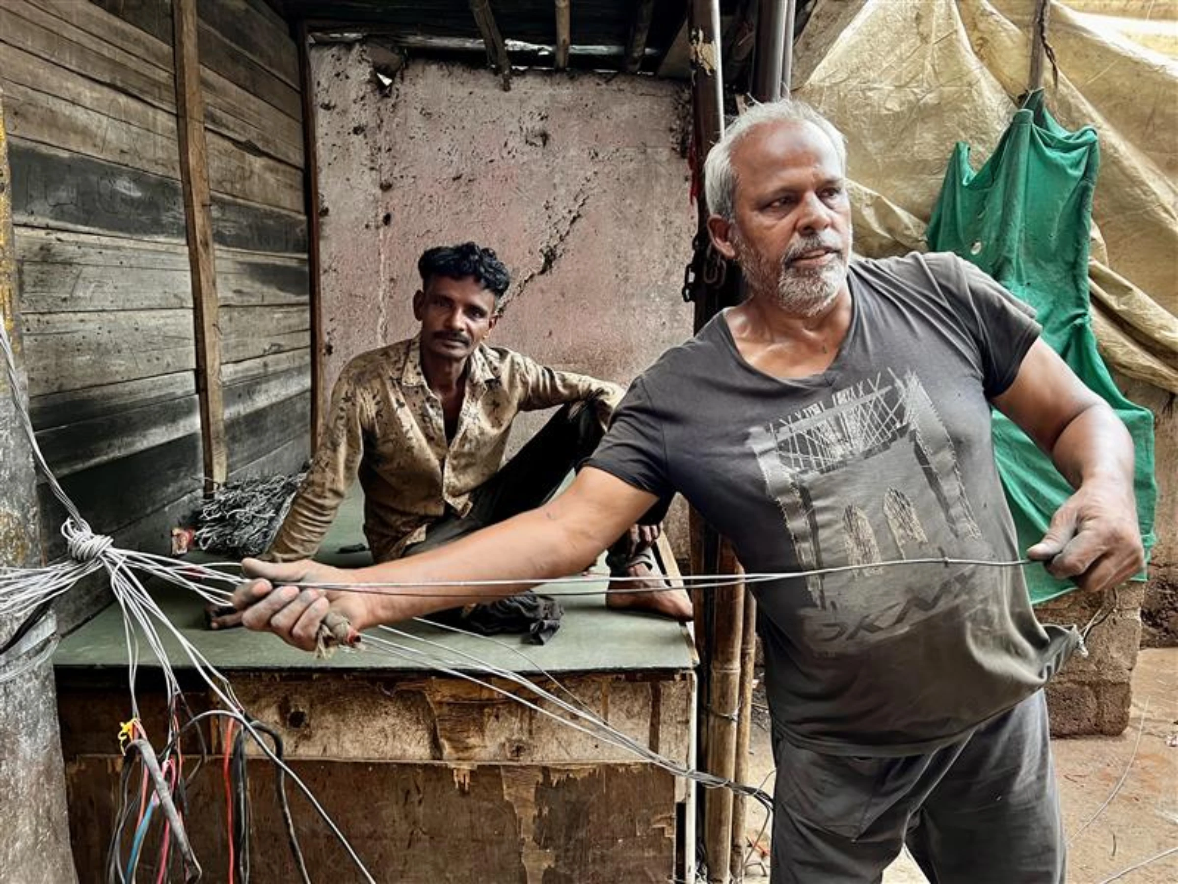 Mohammed Saleem, an informal e-waste recycling worker, peels old wires to extract aluminium and copper in Seelampur, Delhi. July 12, 2025. Thomson Reuters Foundation/Bhasker Tripathi