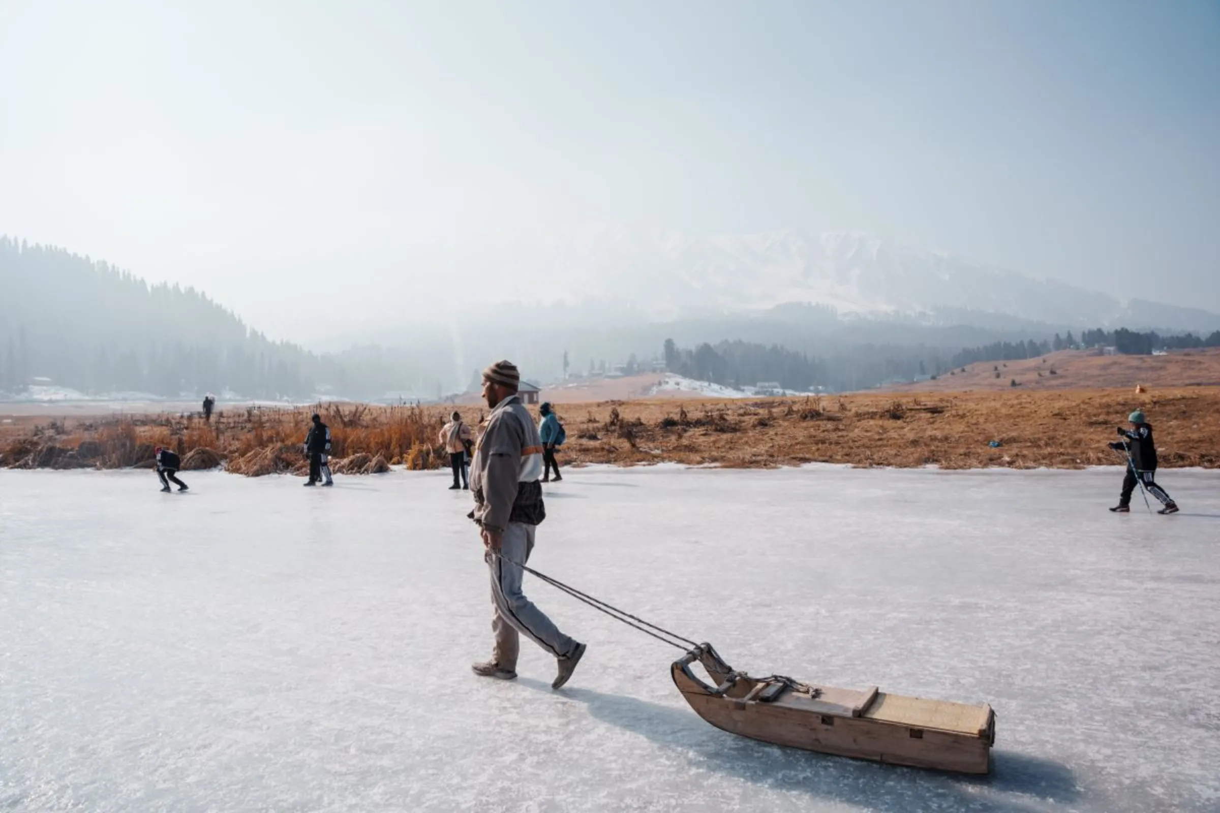 Mohammad Yousuf, 40, drags his sledge across a frozen patch of land at Gulmarg, a Kashmiri winter sports town. The northern Indian region has seen little snowfall this year, Jan. 6, 2024. Thomson Reuters Foundation/Mehran Firdous