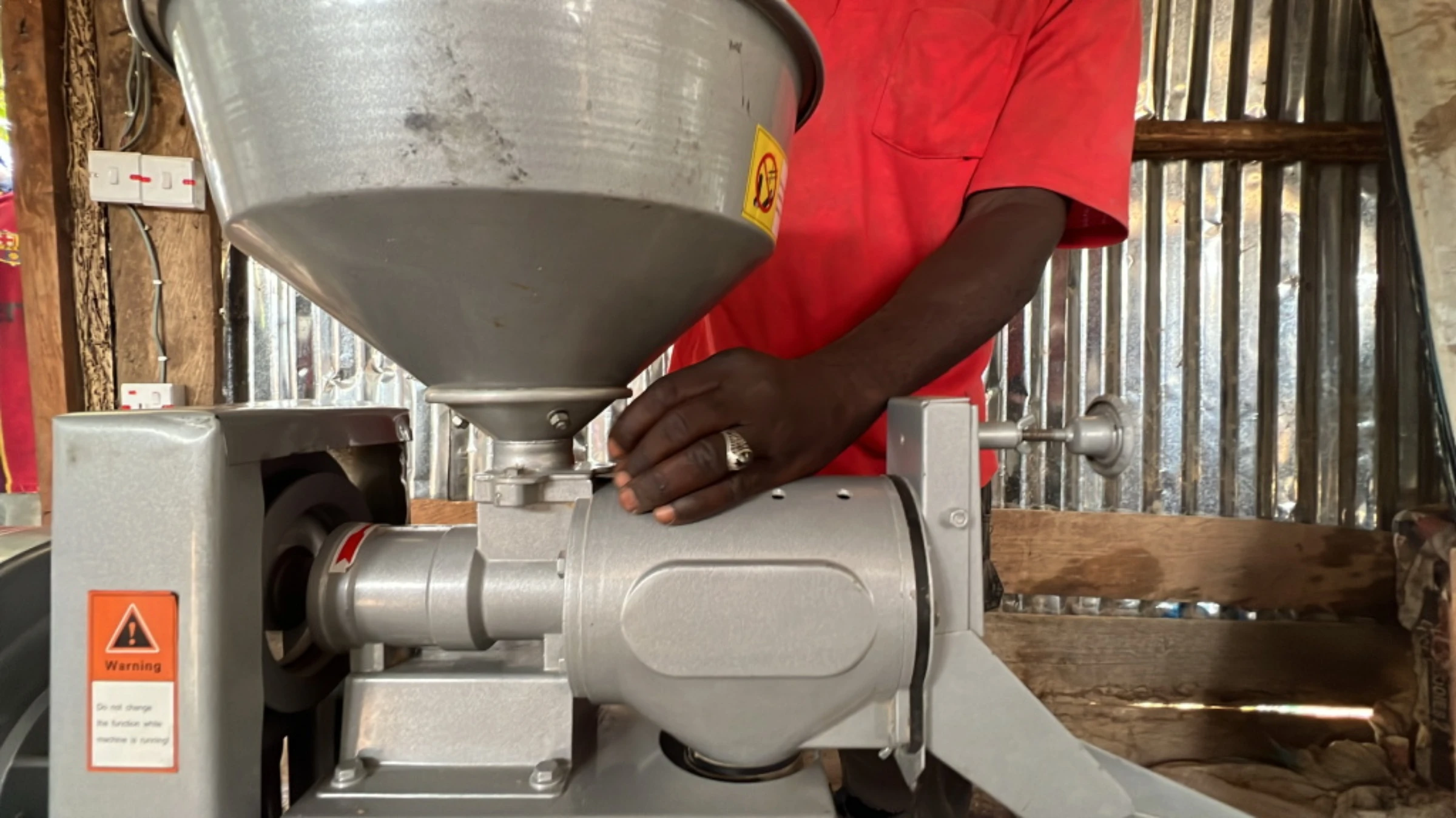 Rice farmer Danjuma Okuwa adjusts his newly installed electric rice milling machine at his compound in Rukubi, Nasarawa, Nigeria, September 27, 2022. Thomson Reuters Foundation/Afolabi Sotunde