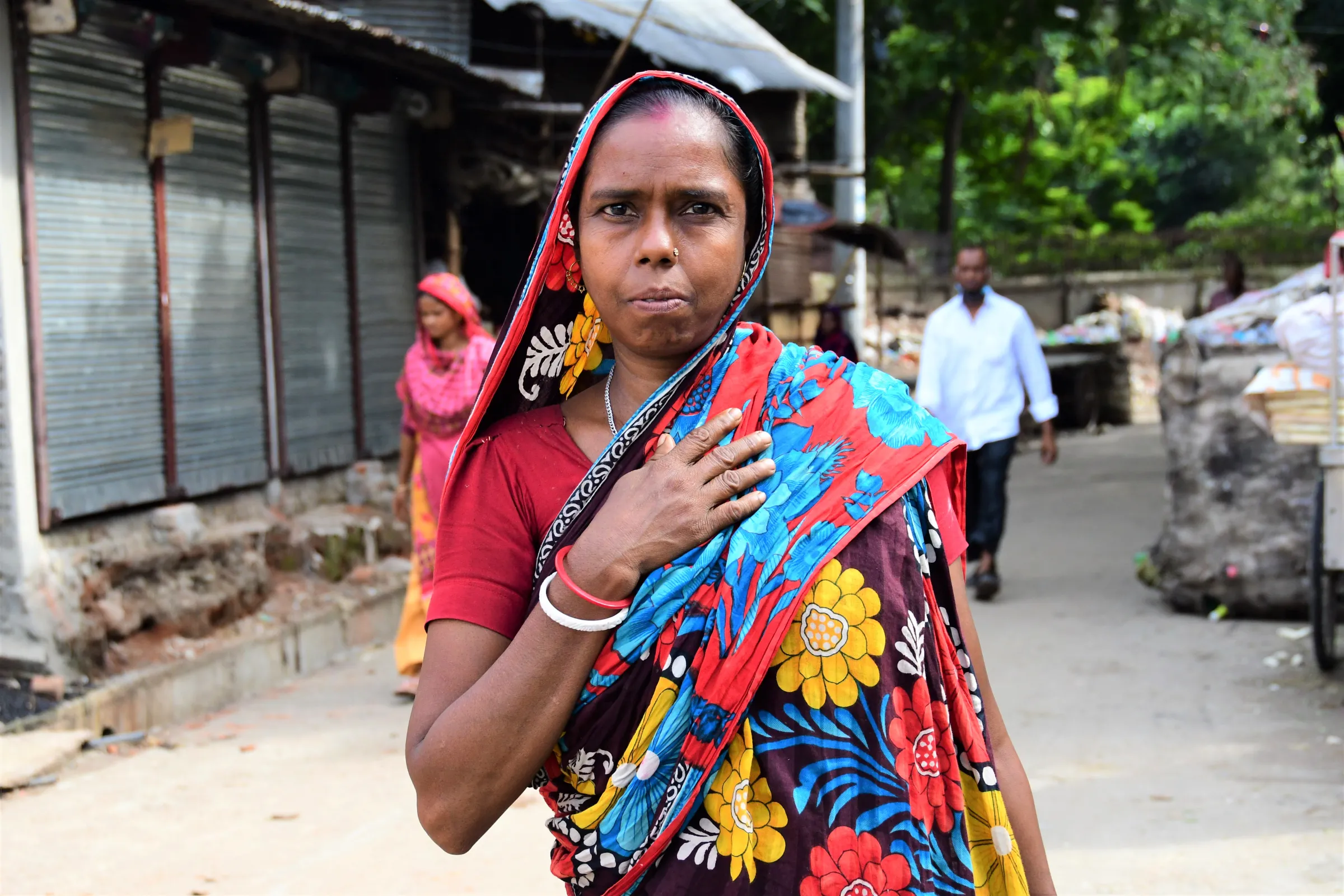 Shanti Dash, a house maid who has been losing her work, stands near closed shops in the Kallyanpur slum in Dhaka, Bangladesh, August 16, 2022. Thomson Reuters Foundation/Mosabber Hossain