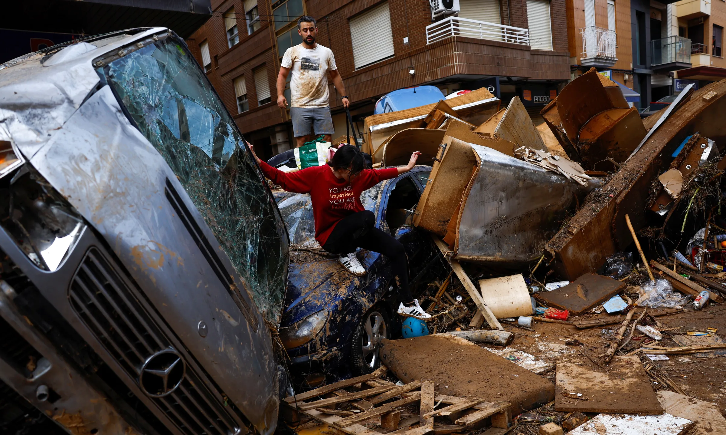 People walk through piled up cars, following floods in Sedavi, Valencia, Spain, October 31, 2024. REUTERS/Susana Vera