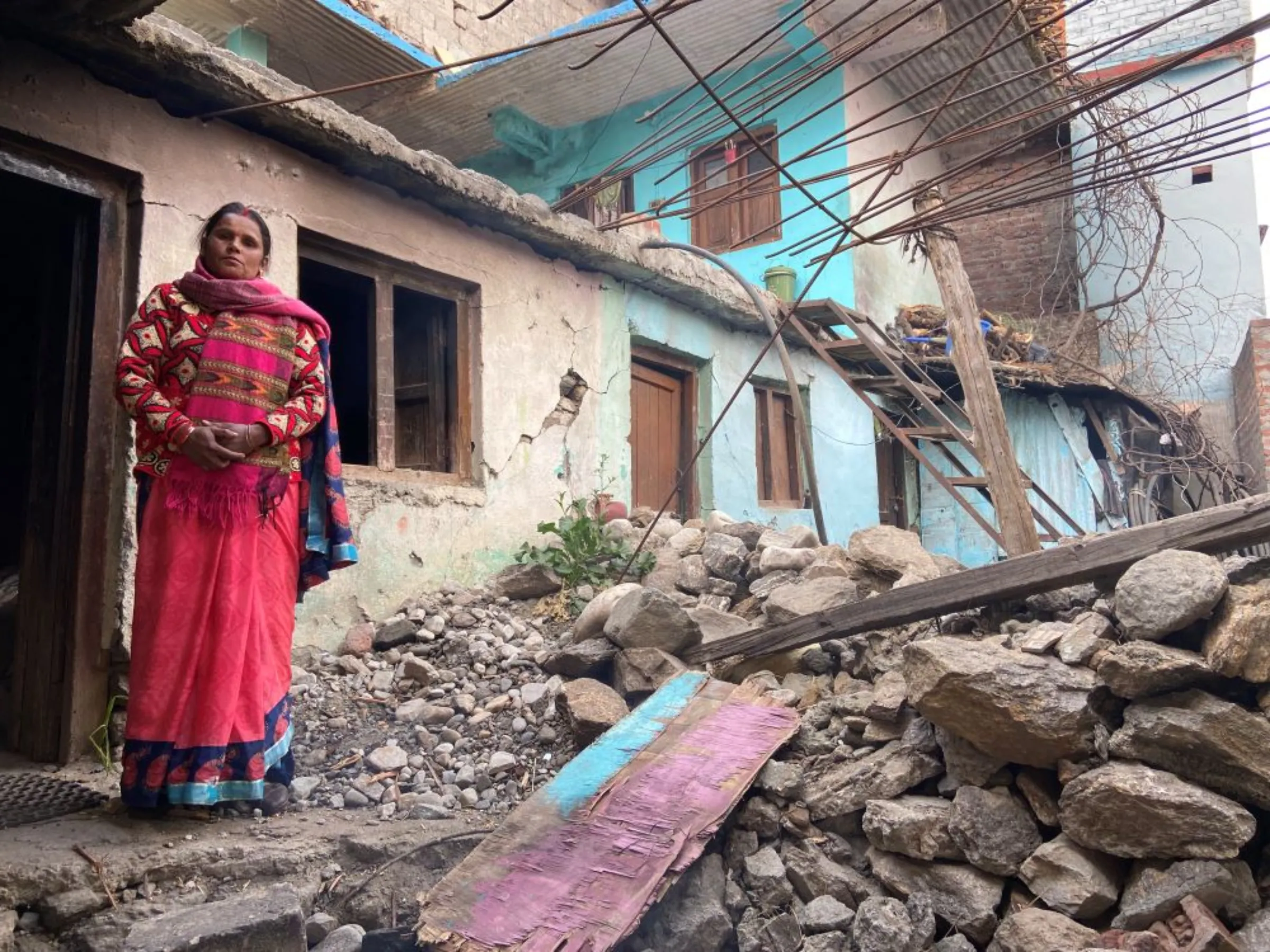 Shashi Devi poses for a picture in front of her house that developed cracks last year in the Himalayan town of Joshimath, India, January 12, 2023