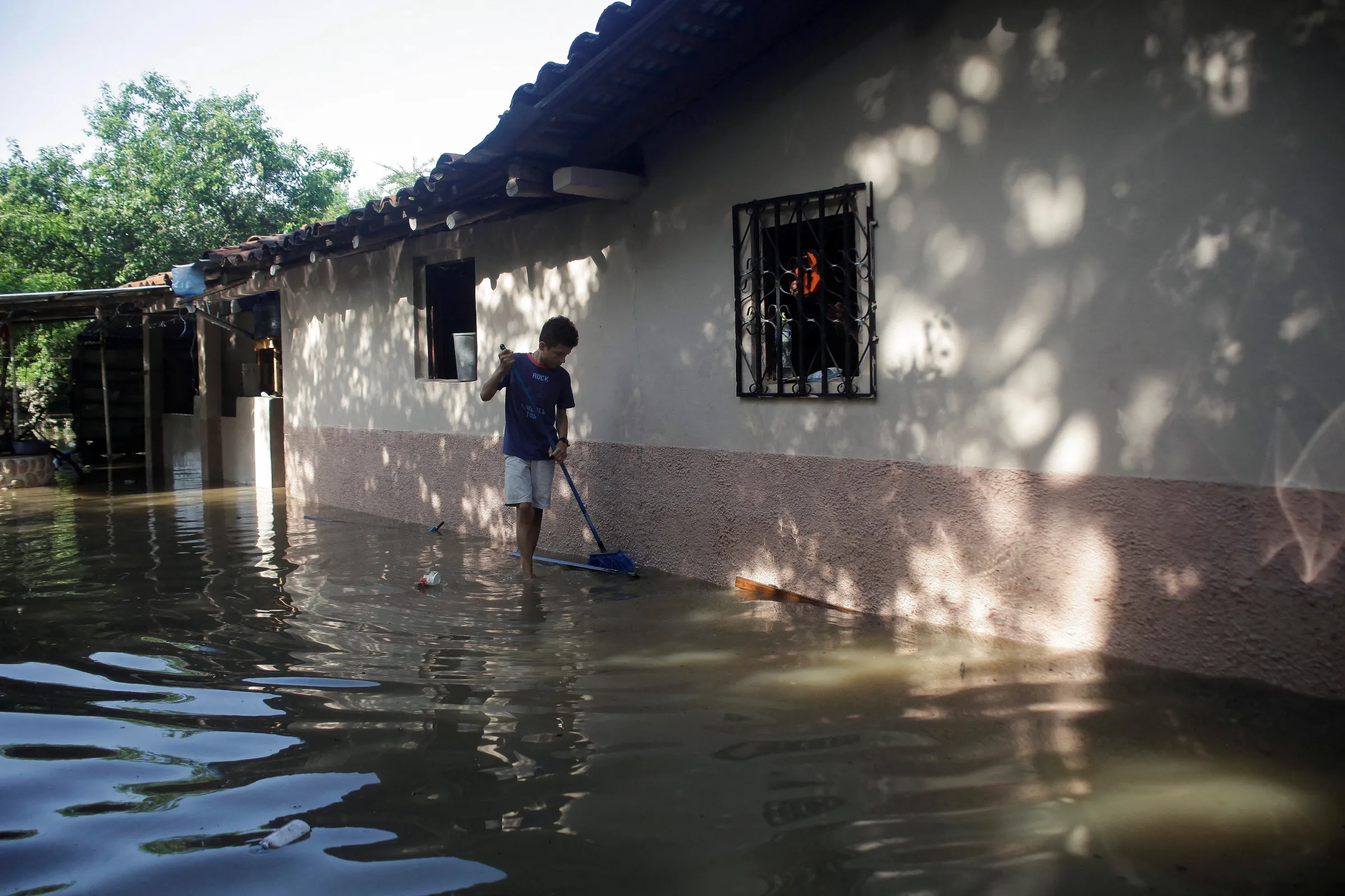 A young man uses a broom near a flooded house after the impact of tropical storm Julia in the department of Valle, Honduras October 11, 2022. REUTERS/Fredy Rodriguez