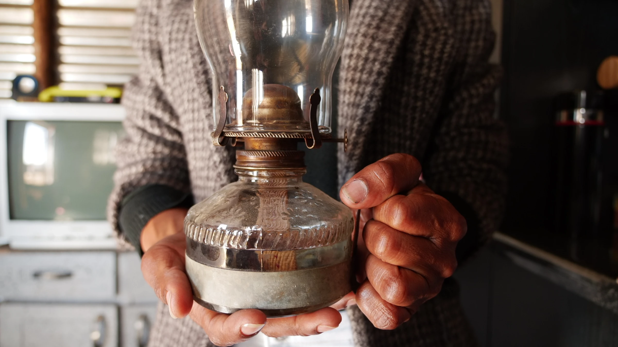Nelly Nkosi, women's officer with the Khuthala Environmental Care Group, holds her empty paraffin lamp in her home in Nomzamo, South Africa, July 10, 2025. Thomson Reuters Foundation/Kim Harrisberg