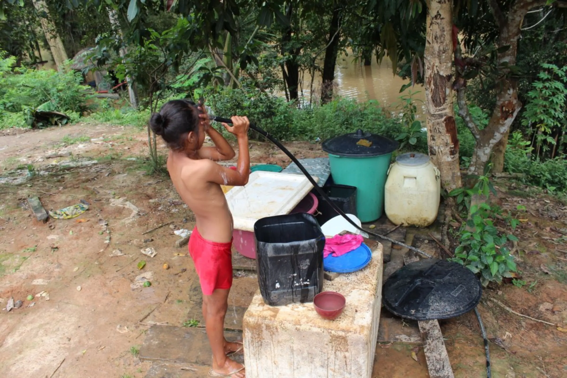 A girl washes with a hose in Pirapitinga, near Humaitá, Brazil, Feb. 28, 2024. Thomson Reuters Foundation/André Cabette Fábio
