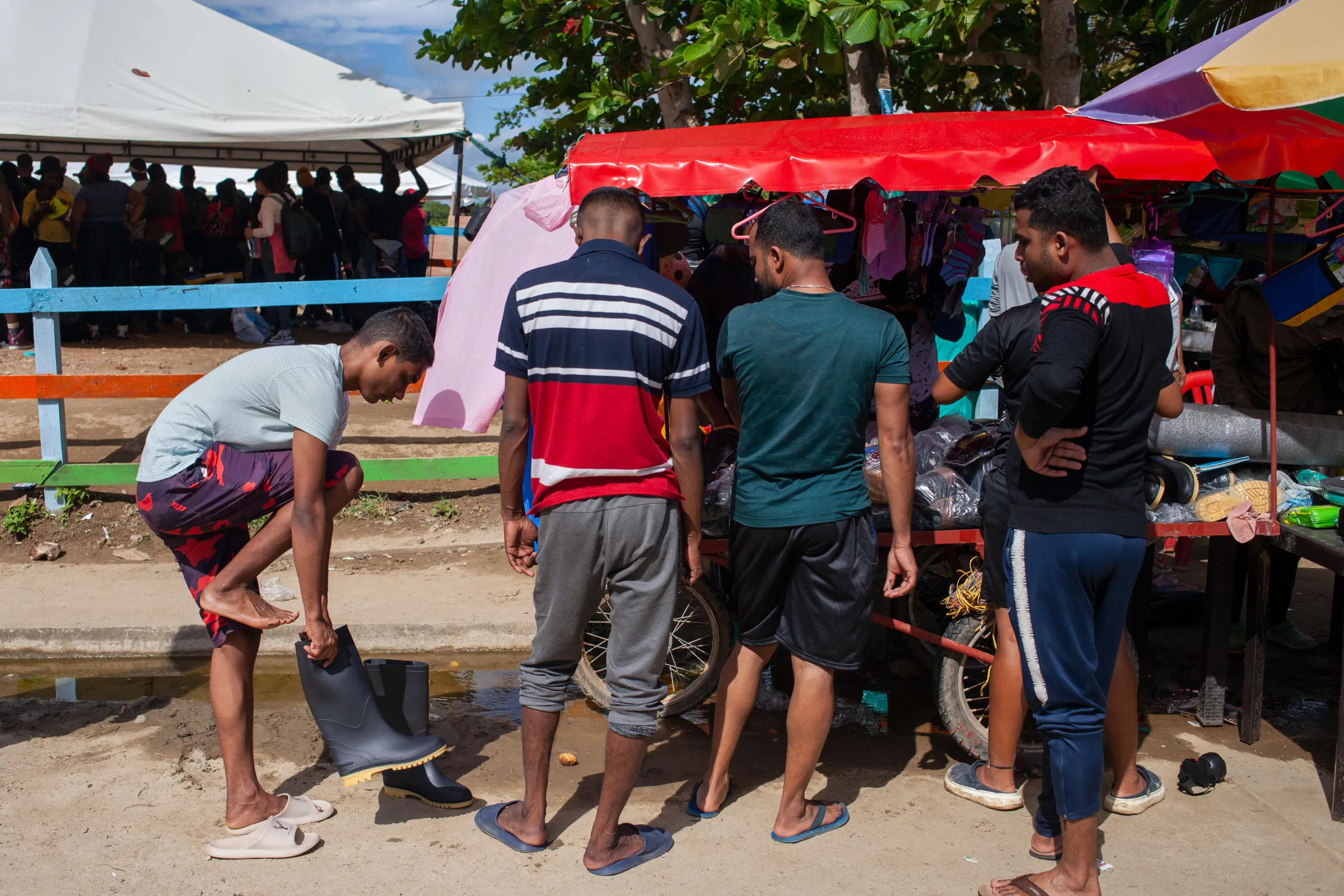 Migrants from Nepal try on rubber boots and buy jungle kit to prepare for the jungle trek through the Darién Gap in the Colombian beach town of Necoclí. Necoclí, Colombia, July 26, 2022. Thomson Reuters Foundation/Fabio Cuttica