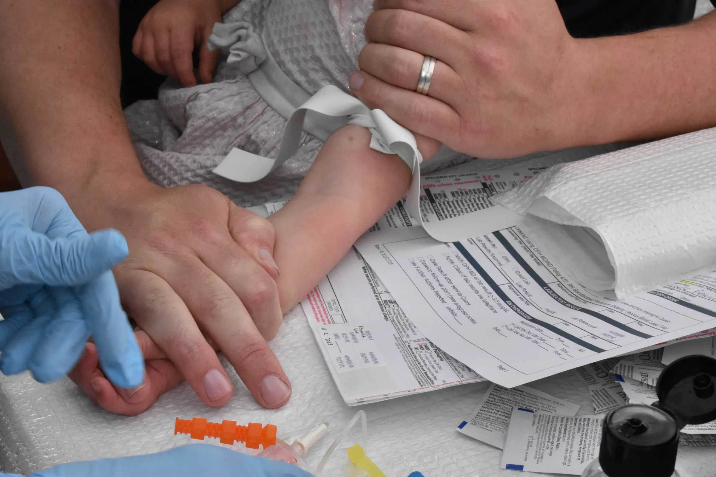 Darcy Fenwick holds 18-month-old Lily Fenwick’s arm while a nurse prepares to take a blood sample, April 27, 2025. Rachel Parsons/Thomson Reuters Foundation