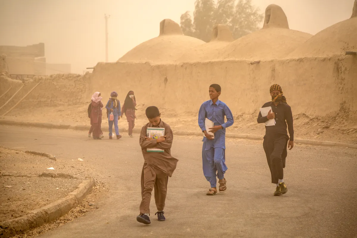 School children walk through one of the many sand and dust storms that hit parts of the Middle East this year