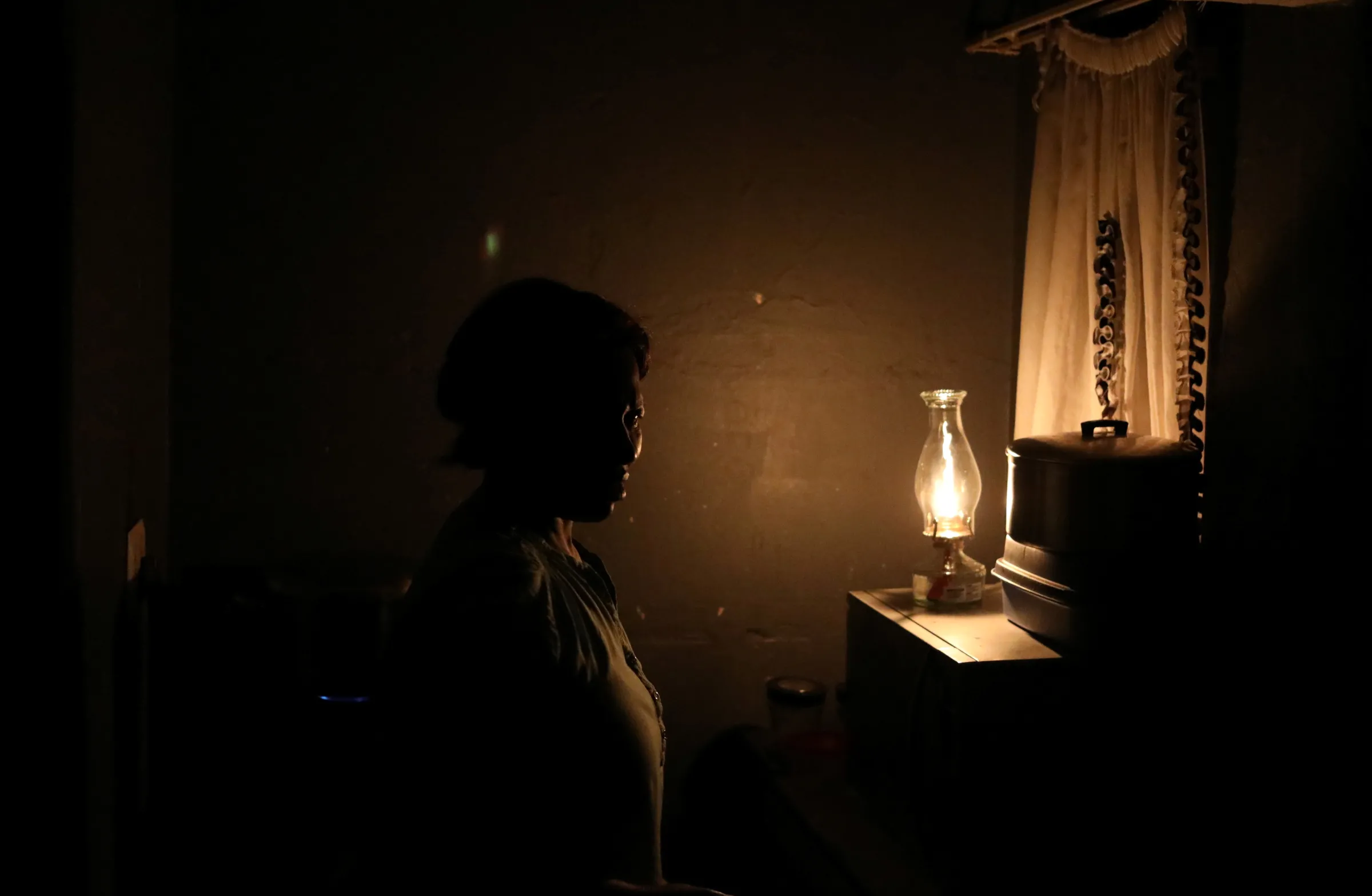 A women looks on next to a parafin light during an electricity load-shedding blackout in Soweto, South Africa, March 18, 2021. REUTERS/Siphiwe Sibeko