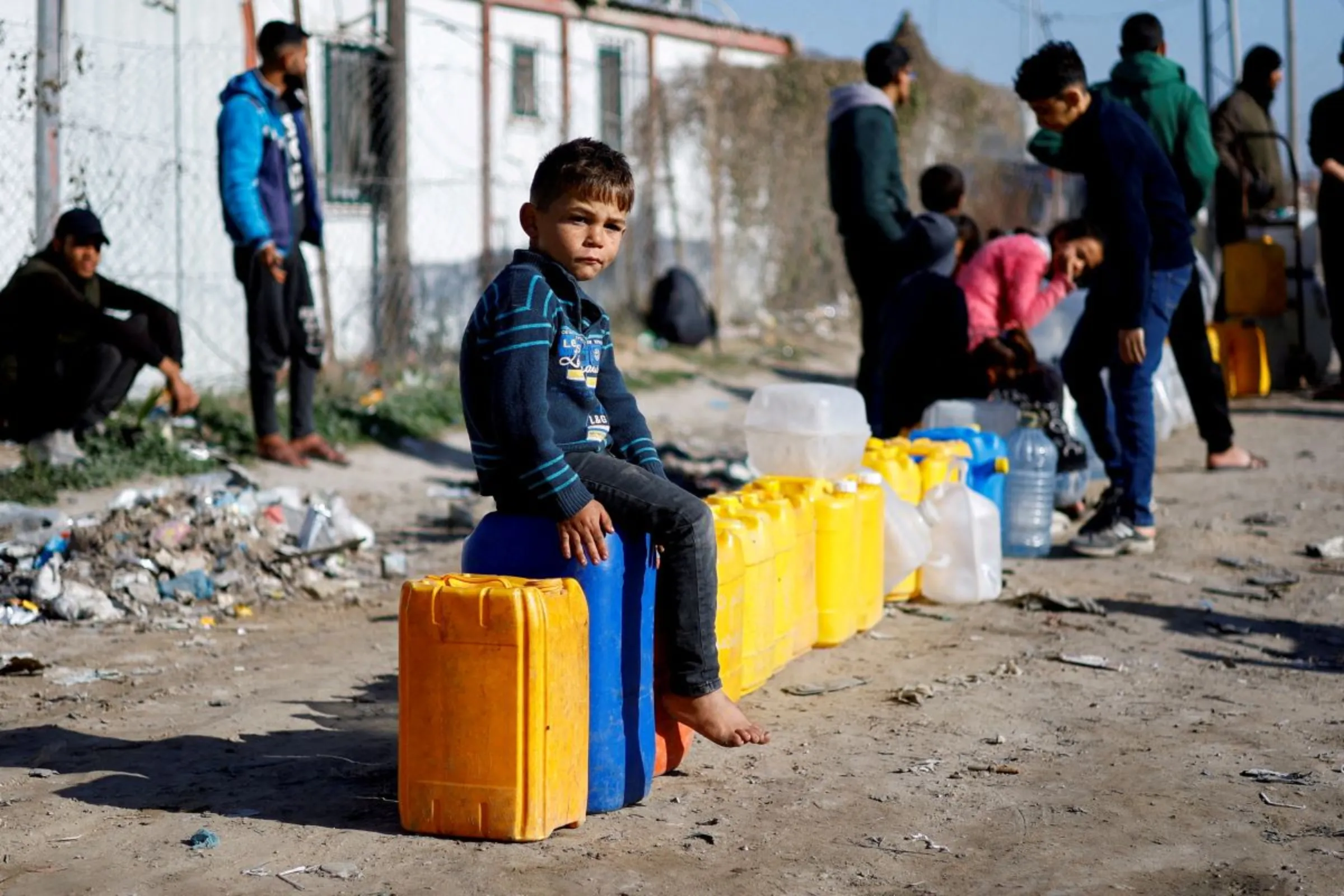 A displaced Palestinian boy, who fled his house due to Israeli strikes, sits on a water canister at a tent camp, amid the ongoing conflict between Israel and the Palestinian Islamist group Hamas, in Rafah in the southern Gaza Strip, January 18, 2024. REUTERS/Ibraheem Abu Mustafa