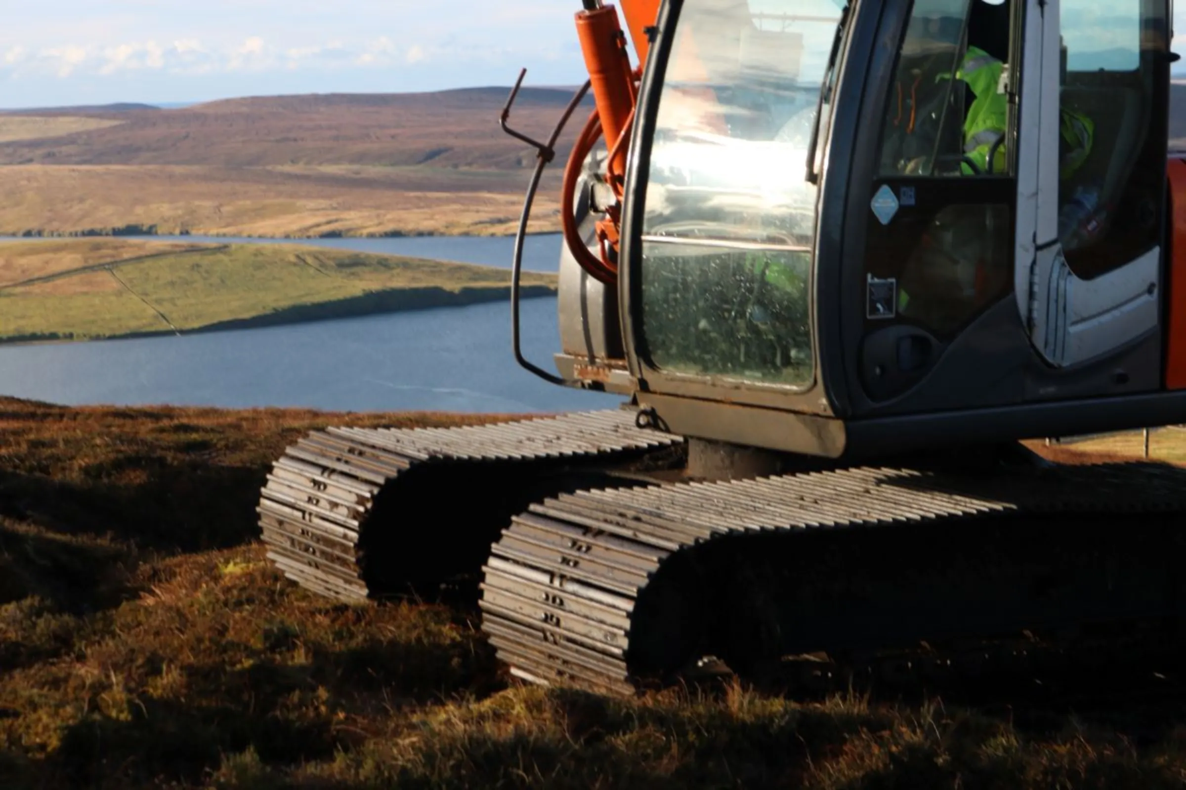 A peatland restorer operates a digger to reshape the damaged edges of bogs to create a gentler slope that reduces erosion, at a peatland restoration site on Mainland island near Tresta hamlet, Shetland, Scotland, November 1, 2023. Thomson Reuters Foundation/Jack Graham