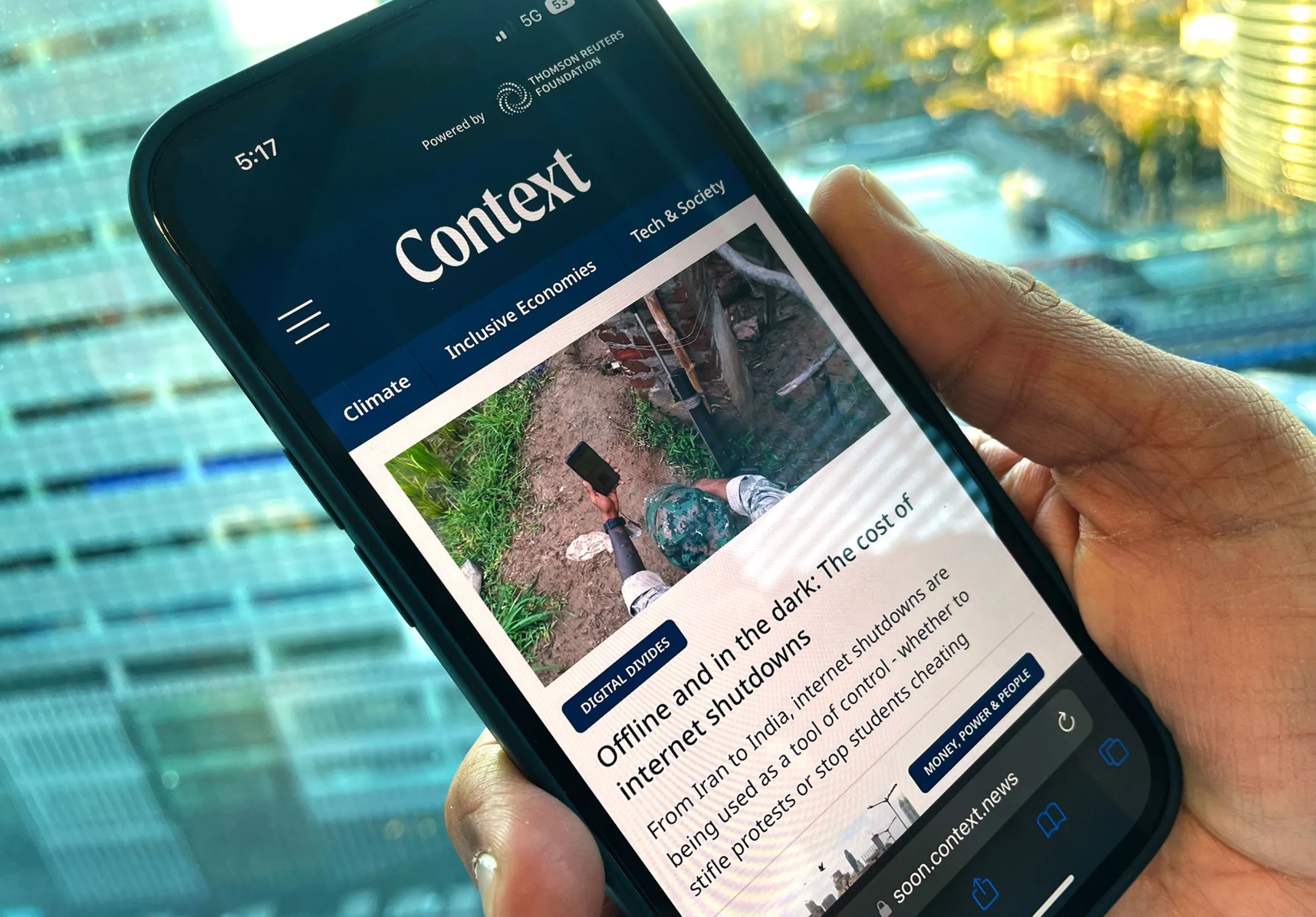 A man holds a mobile phone showing context.news in this illustration photo taken in London, United Kindom. September 28, 2022 Thomson Reuters Foundation/Kevin Mentel