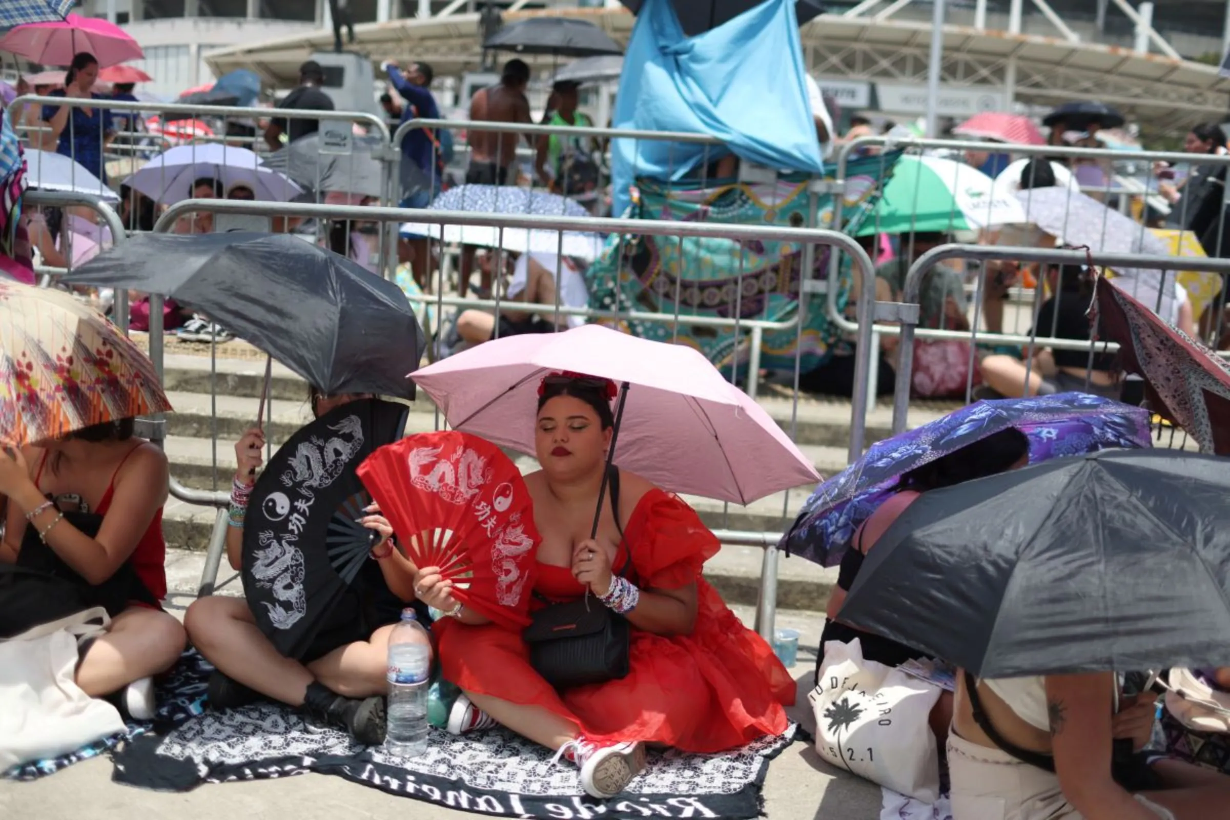 A girl using a fan waits among other people before the Taylor Swift concert, following the death of a fan due to the heat during the first day concert, in Rio de Janeiro, Brazil