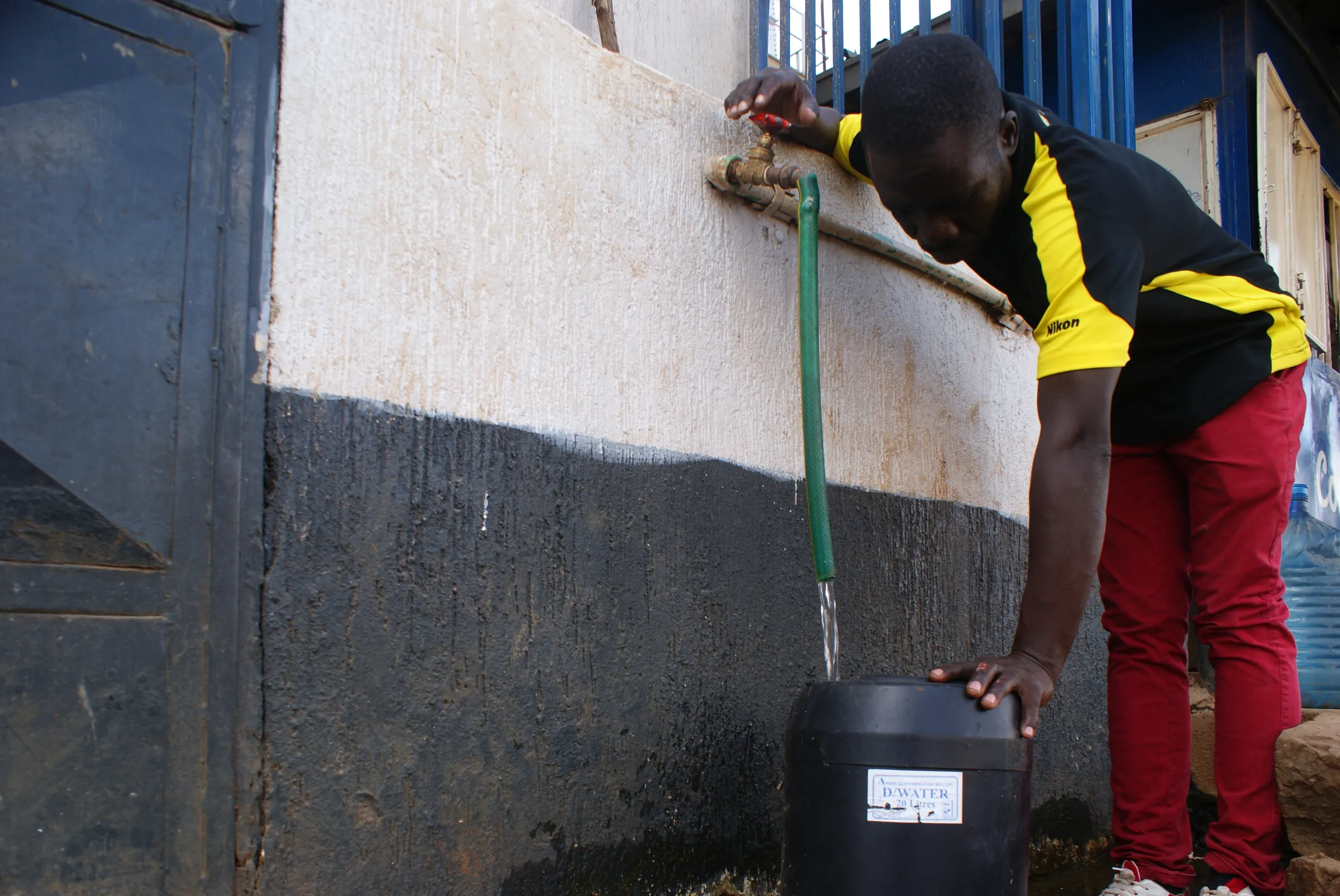 A resident fetching water at the Human Needs Project facility in the Kibera slum in Nairobi, Kenya. May 20, 2022. Thomson Reuters Foundation/Kagondu Njagi