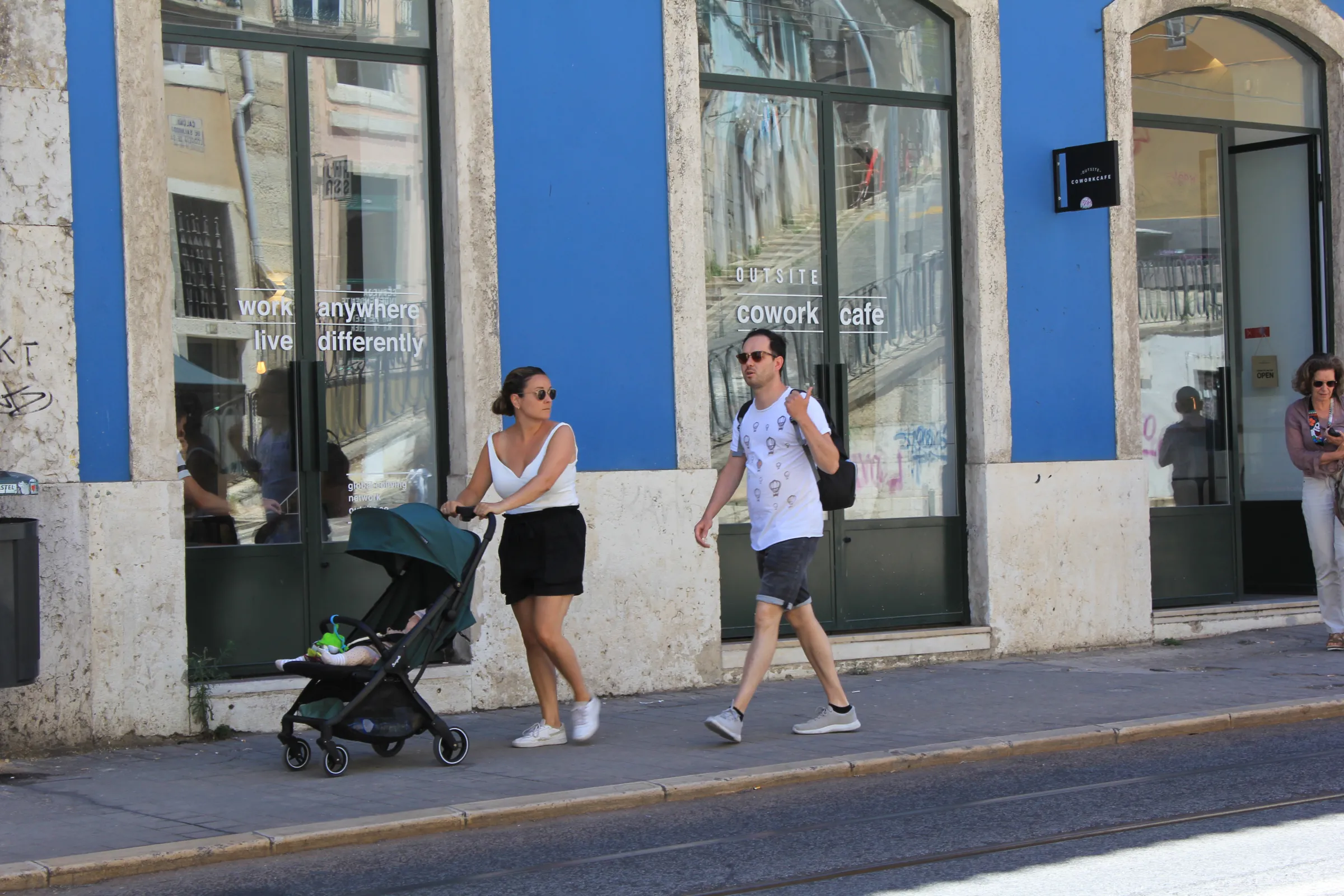 A woman pushes a pram down the street in Portugal