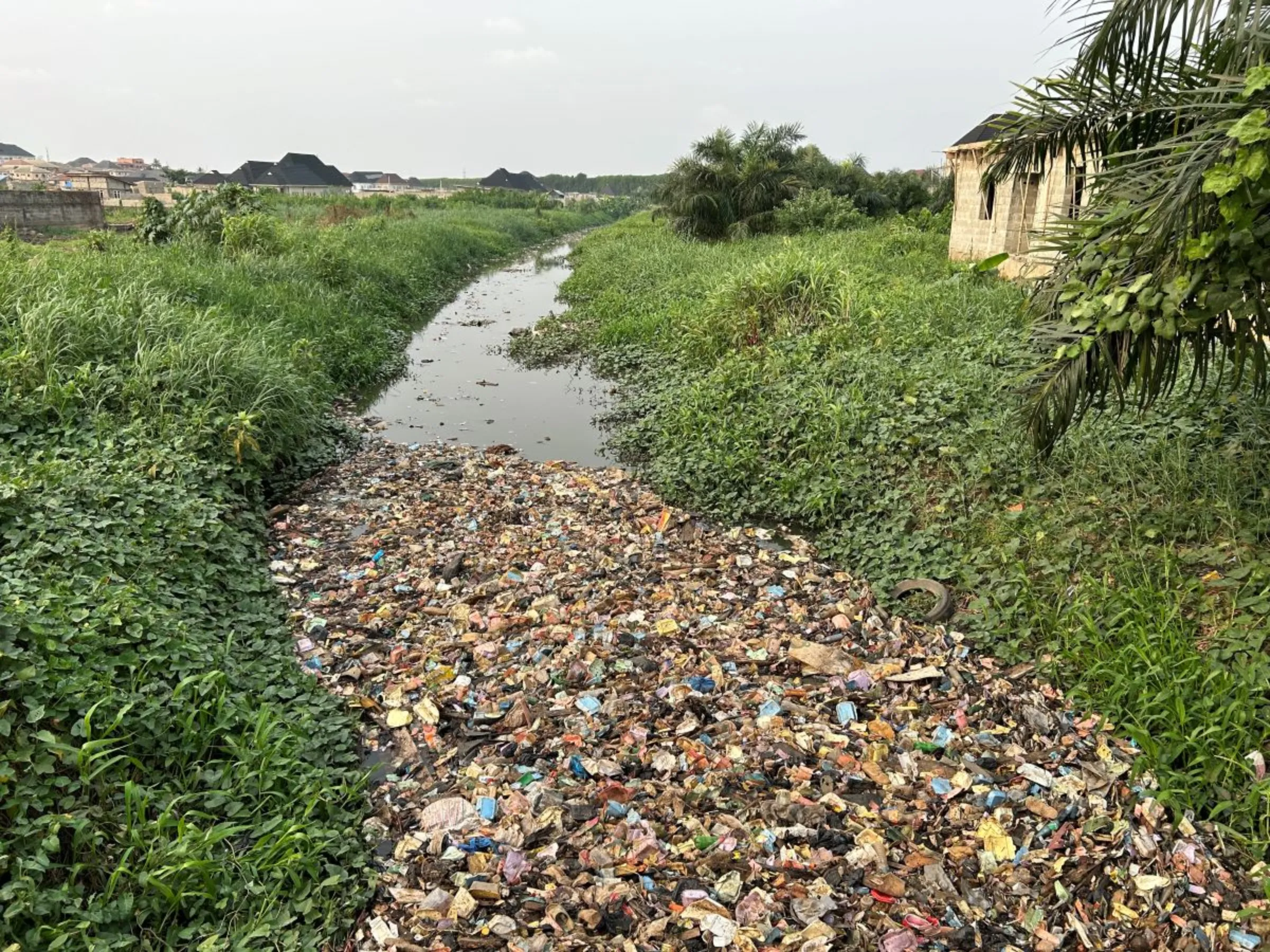 Used plastics and waste block a canal in Lagos district on February 20, 2024. Bukola Adebayo/ Thomson Reuters Foundation