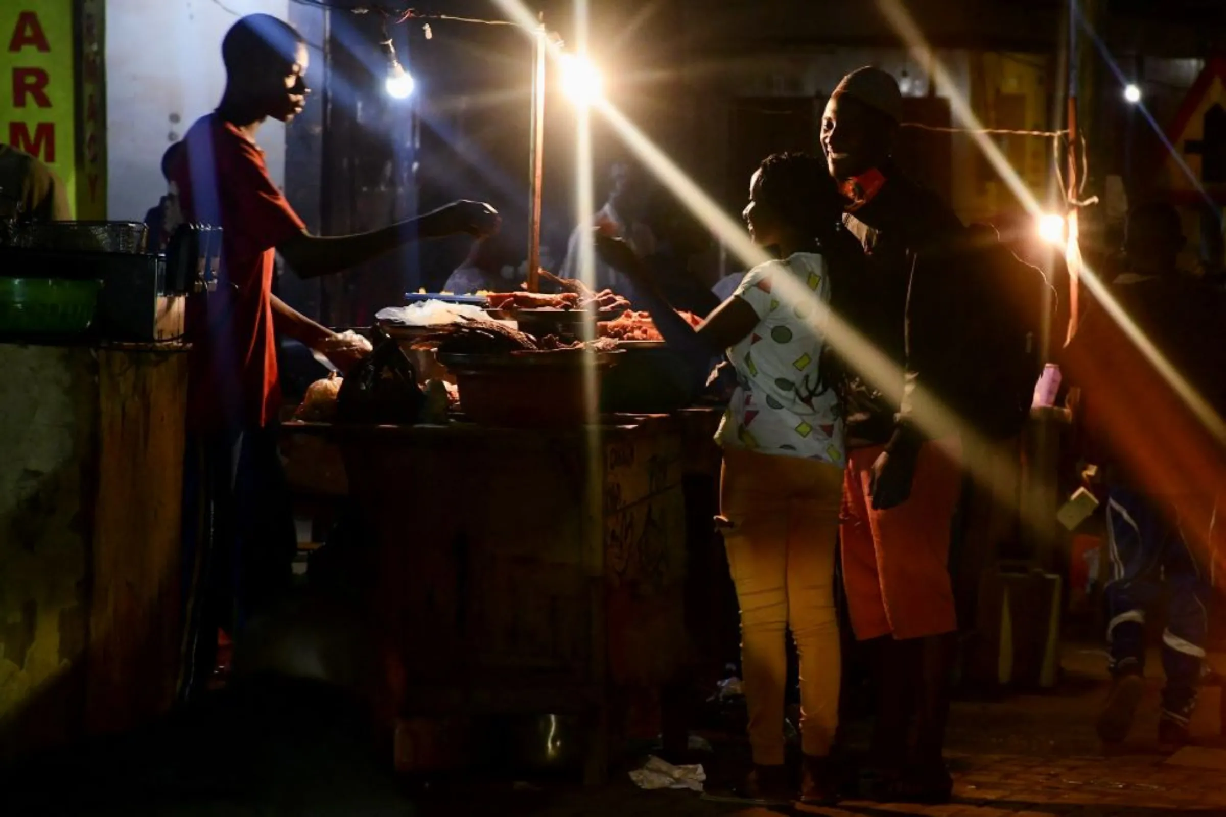 A street food vendor sells barbecue chicken to customers, after Uganda’s president Yoweri Museveni reopened the economy which permitted bars and musicians to perform amid the coronavirus disease (COVID-19) containment efforts, in Nakulabye suburb of Kampala, Uganda January 31, 2022. REUTERS/Abubaker Lubowa