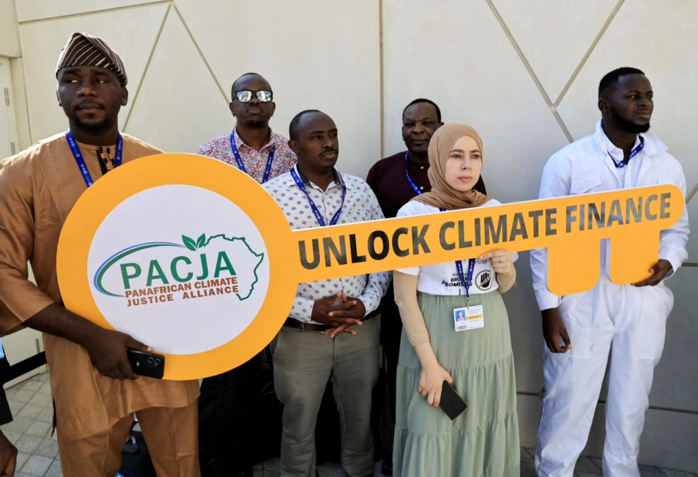Activists hold a sign that reads 'Unlock Climate Finance' at the United Nations Climate Change Conference COP28 in Dubai, United Arab Emirates, December 5, 2023. REUTERS/Thaier Al-Sudani