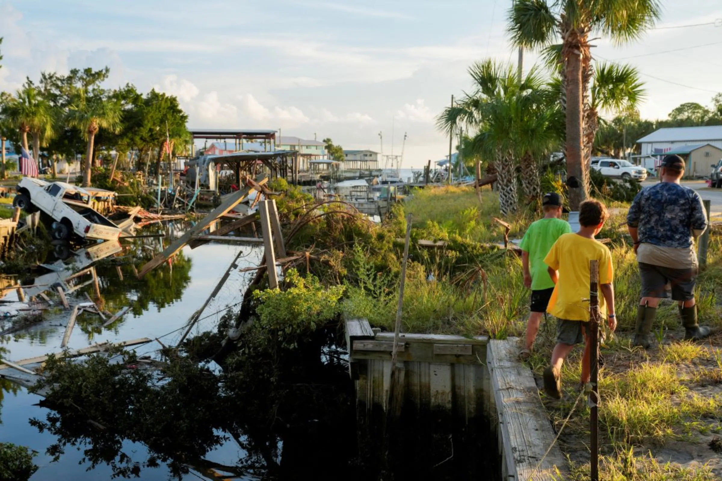 Boys walk past a canal littered with debris after Hurricane Idalia hit Horseshoe Beach, Florida, U.S., Aug. 31, 2023. REUTERS/Cheney Orr