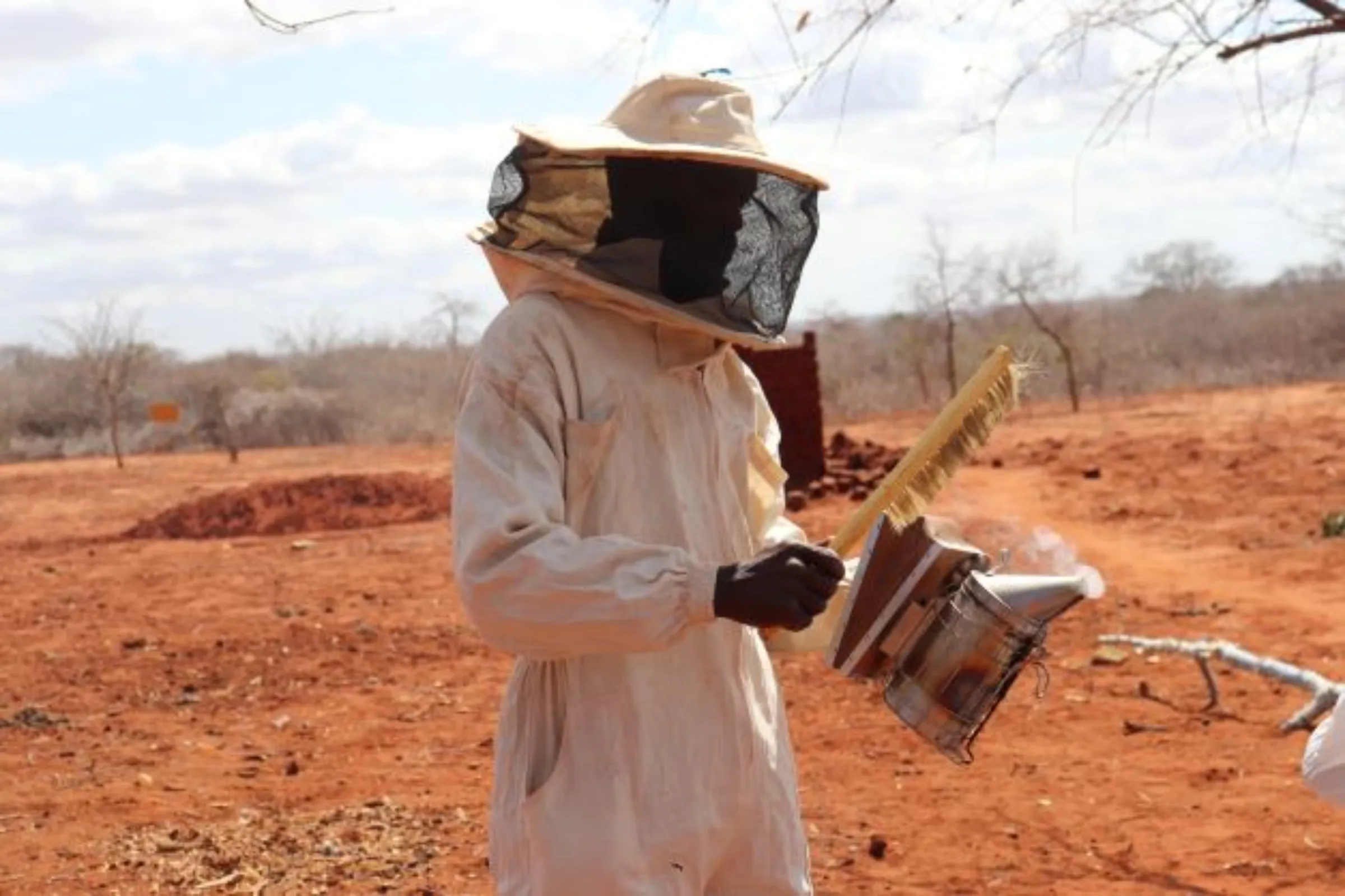 A farmer demonstrates how to use smoke when harvesting honey from beehives in Mware village, Kenya, October 13, 2022. Thomson Reuters Foundation/Dominic Kirui