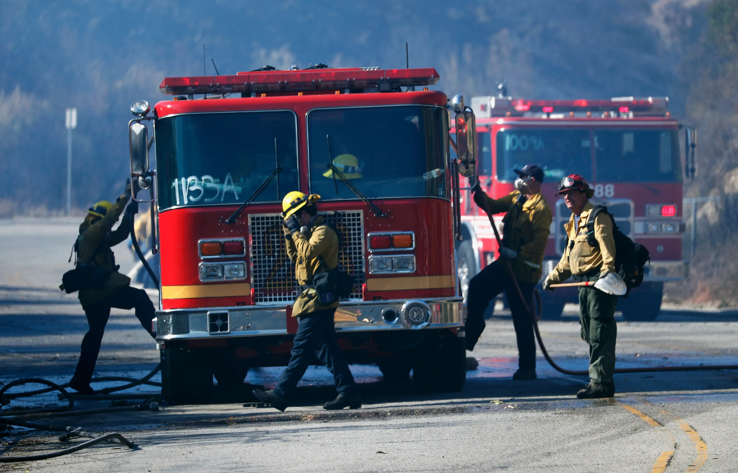 Firefighters gather around a fire truck as they battle the Woolsey fire in West Hills, Southern California, U.S. November 11, 2018. REUTERS/Mario Anzuoni