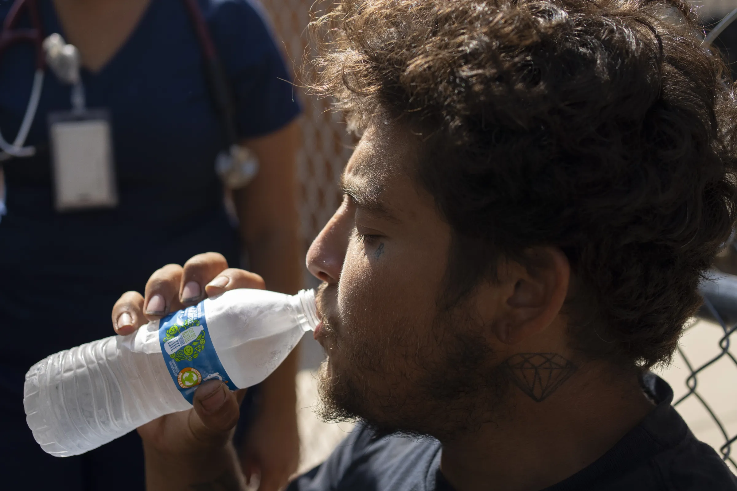 Unhoused street resident Philip Higgens has a drink of water while receiving medical aid after being hit by a car in Phoenix, Arizona. July 15, 2024. Thomson Reuters Foundation/Rebecca Noble