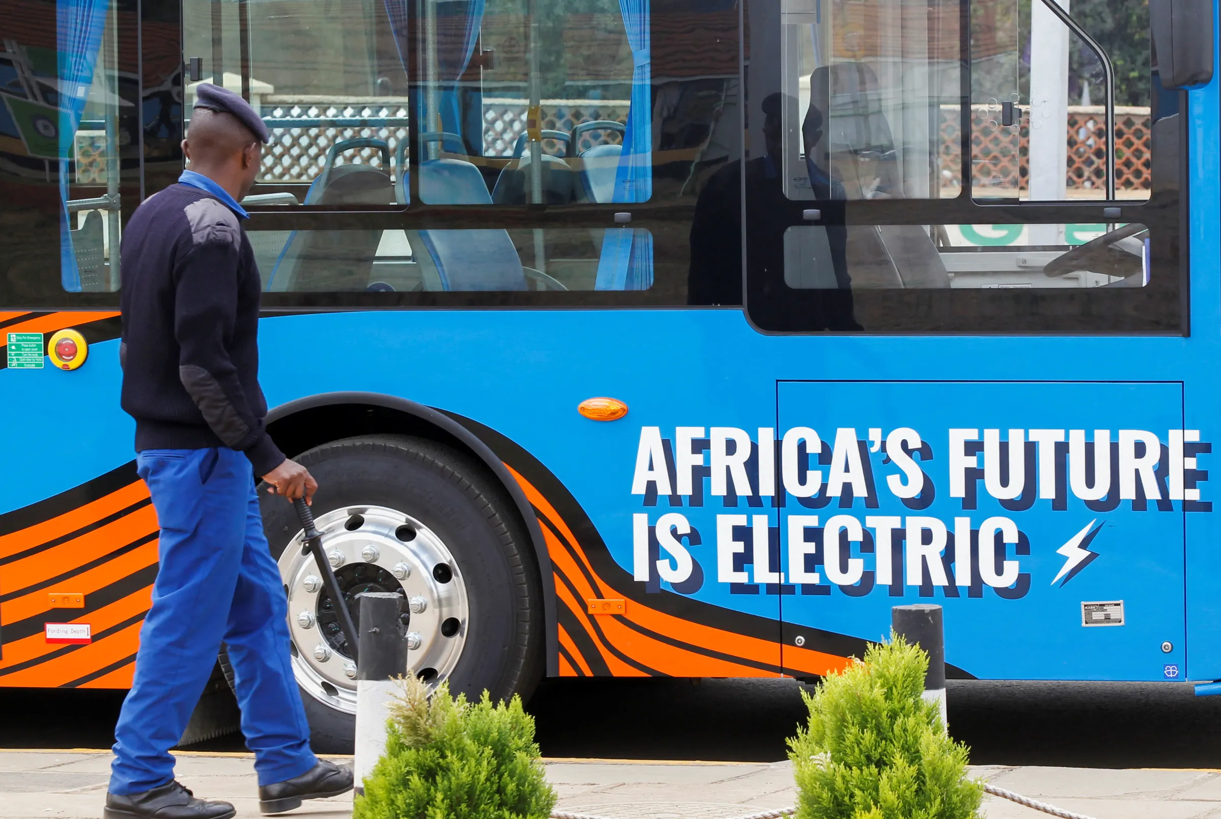 A police officer walks next to an electric mass transit bus assembled by electric vehicle manufacturer Roam at the Green Park Terminus in Nairobi, Kenya October 19, 2022. REUTERS/Monicah Mwangi