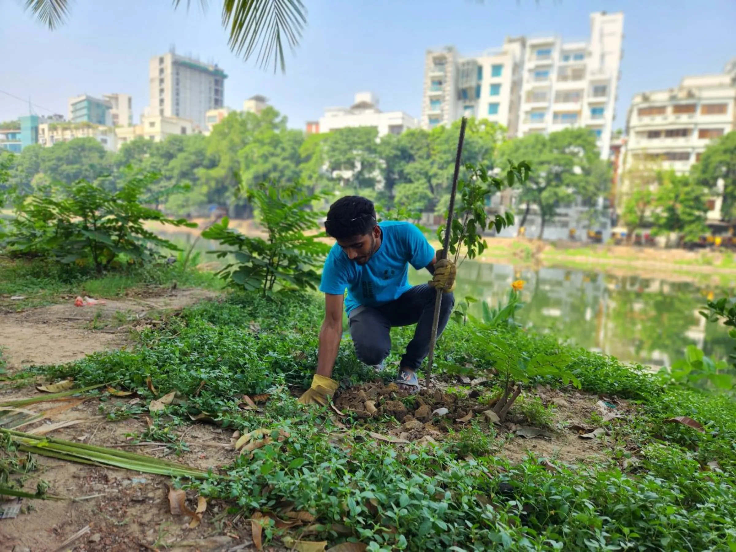 Volunteer Nayon Sorkar tending plants as part of the Gulshan Lakeside greening initiative in Dhaka, Bangladesh, April 26, 2024. Thomson Reuters Foundation/Mosabber Hossain