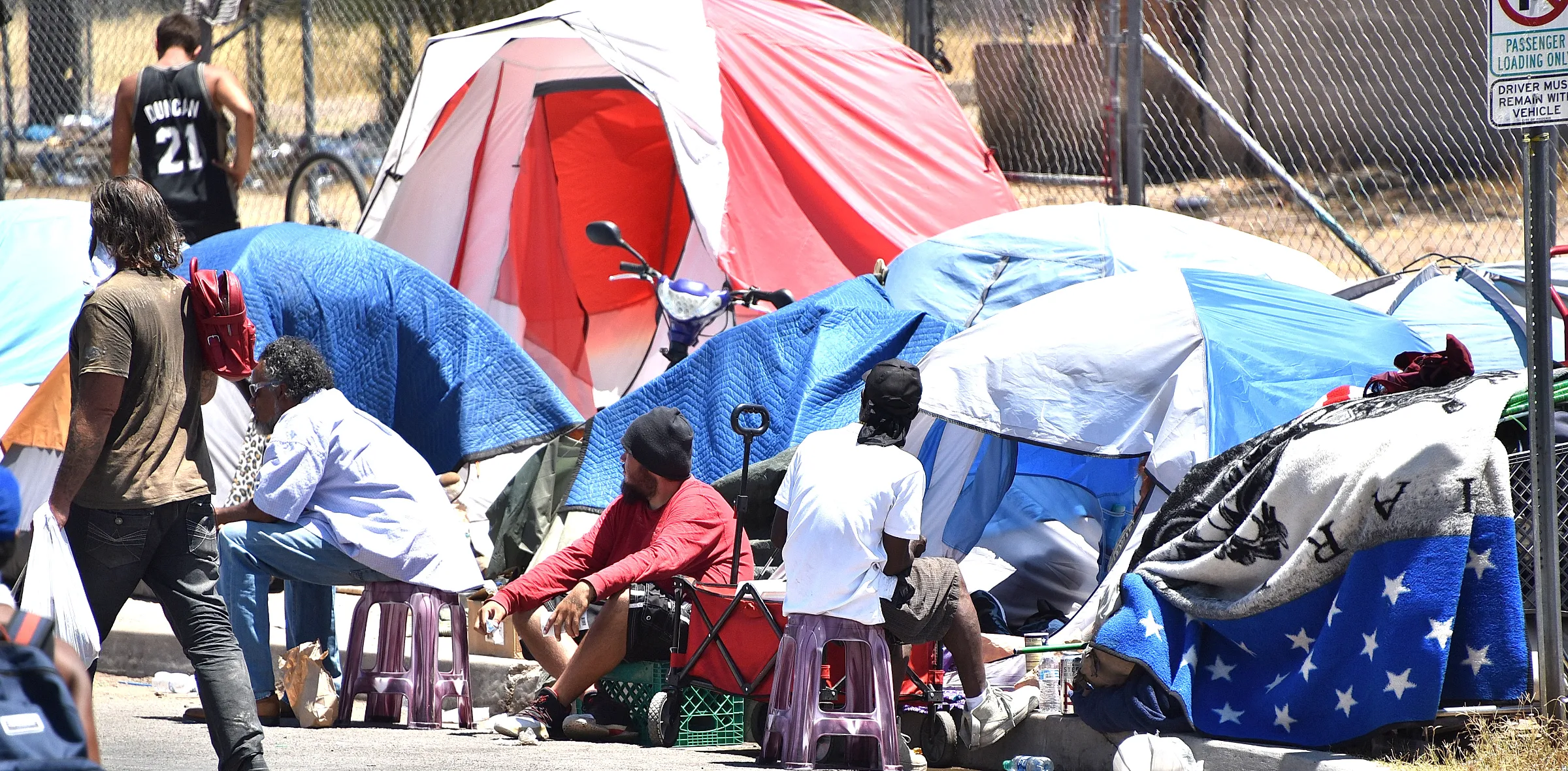 People sit outside a row of tents